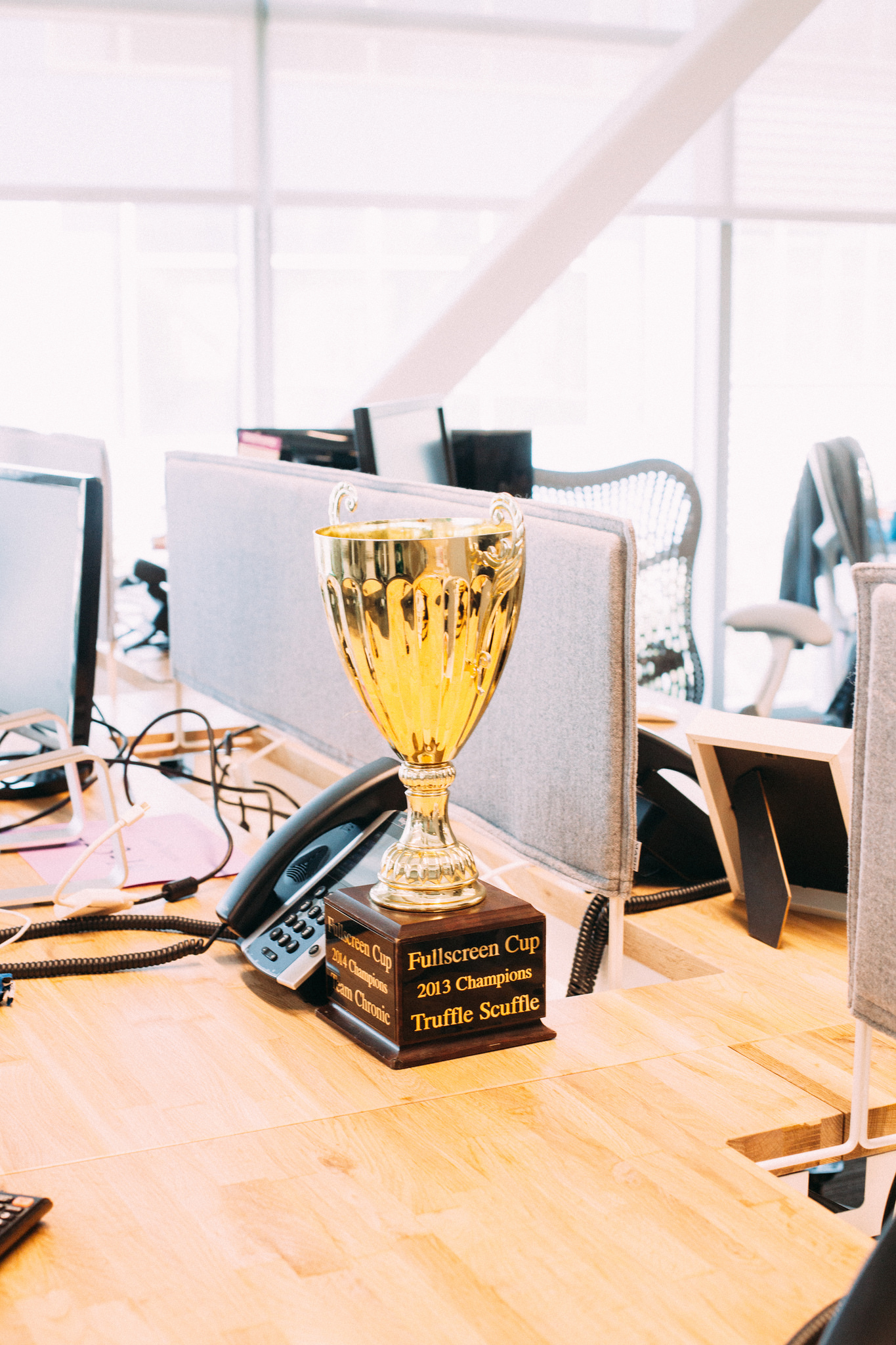 Office desk gold trophy engraved with 'Fullscreen Cup 2013 Truffle Scuffle' and '2014 Team Chronic'.
