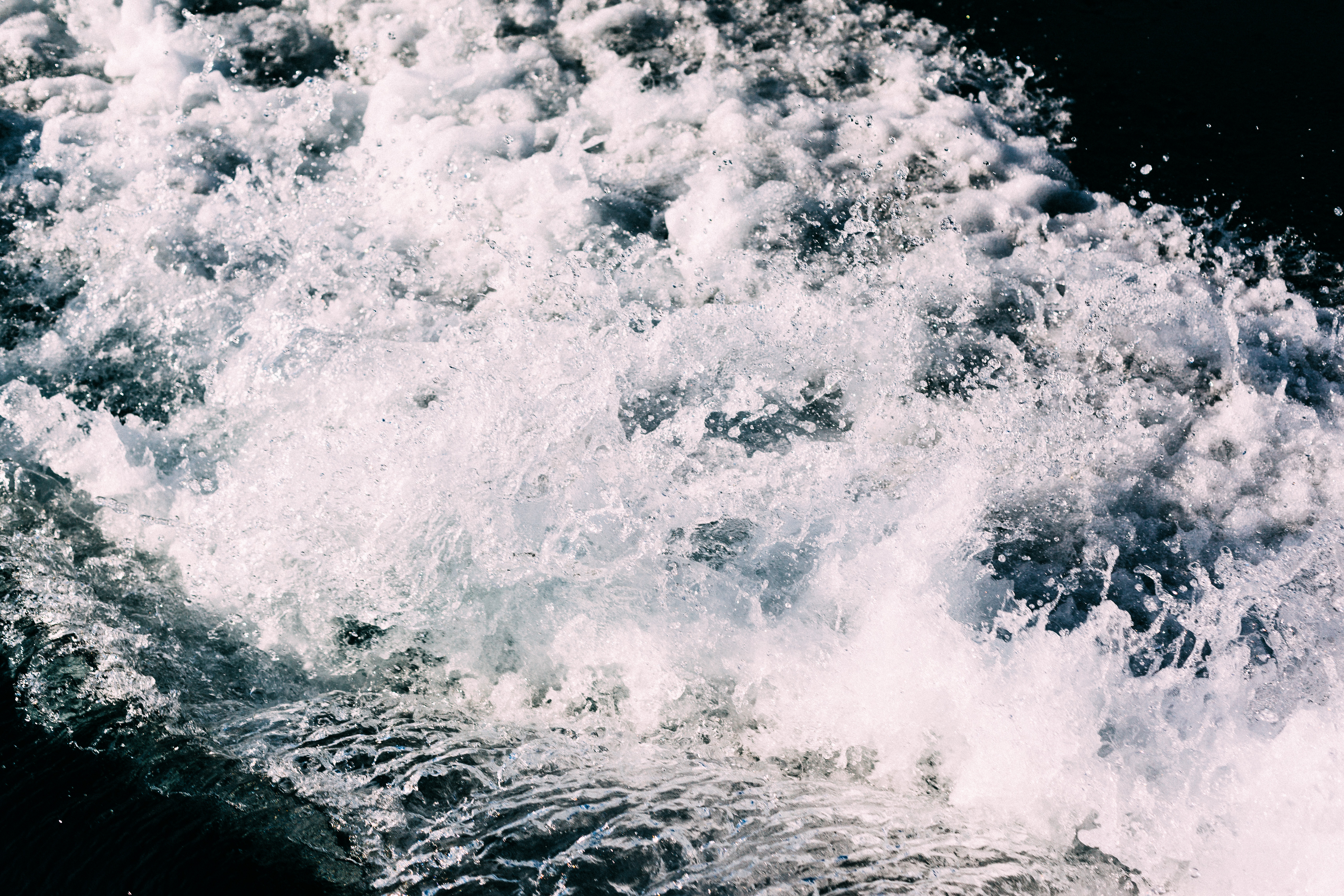 Dynamic close-up shot of frothy white water churning and splashing in the wake of a motorboat, shot with a Canon 5D Mark II.