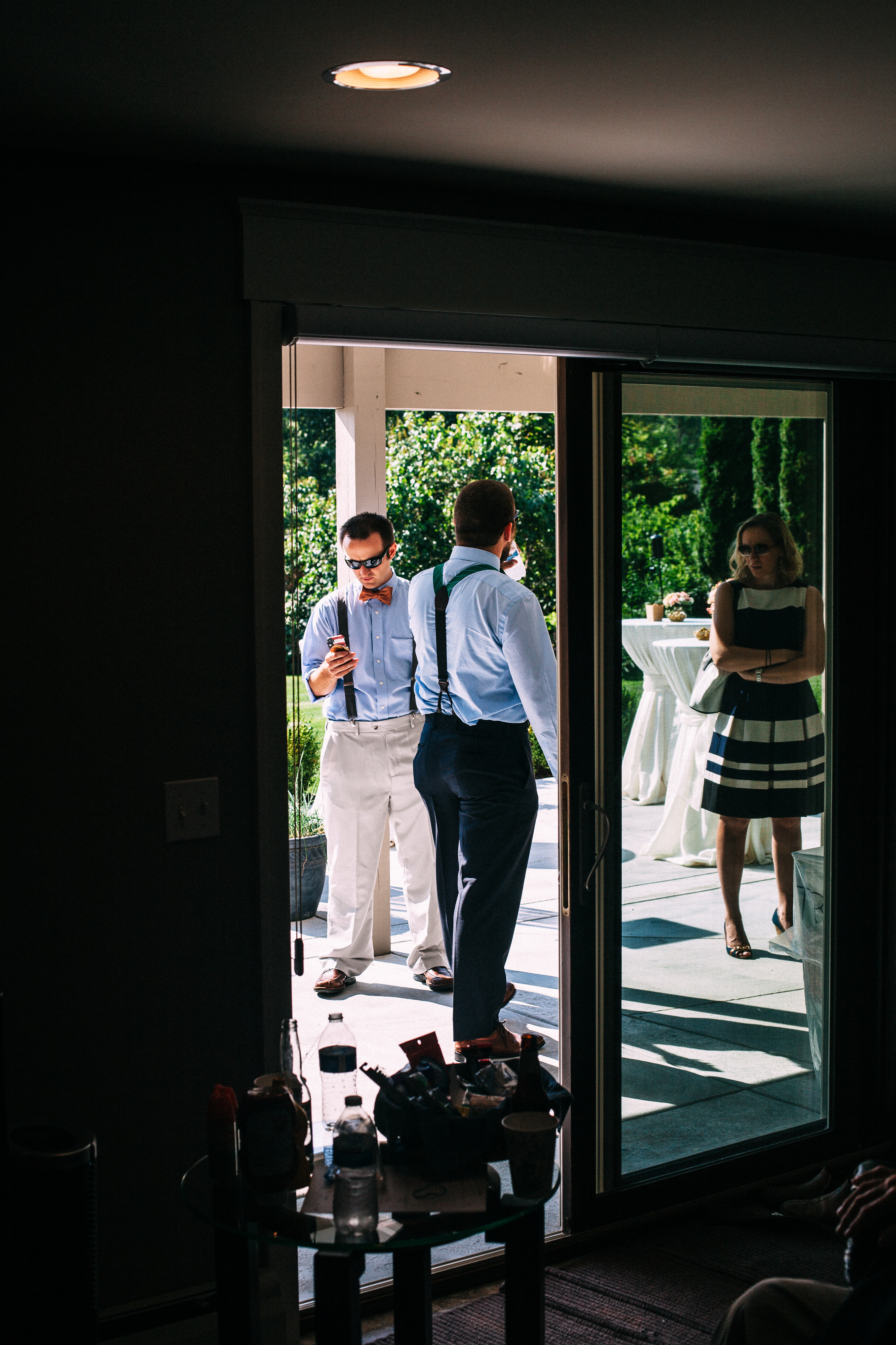 View through sliding glass doors at an outdoor wedding reception patio with guests mingling in evening.