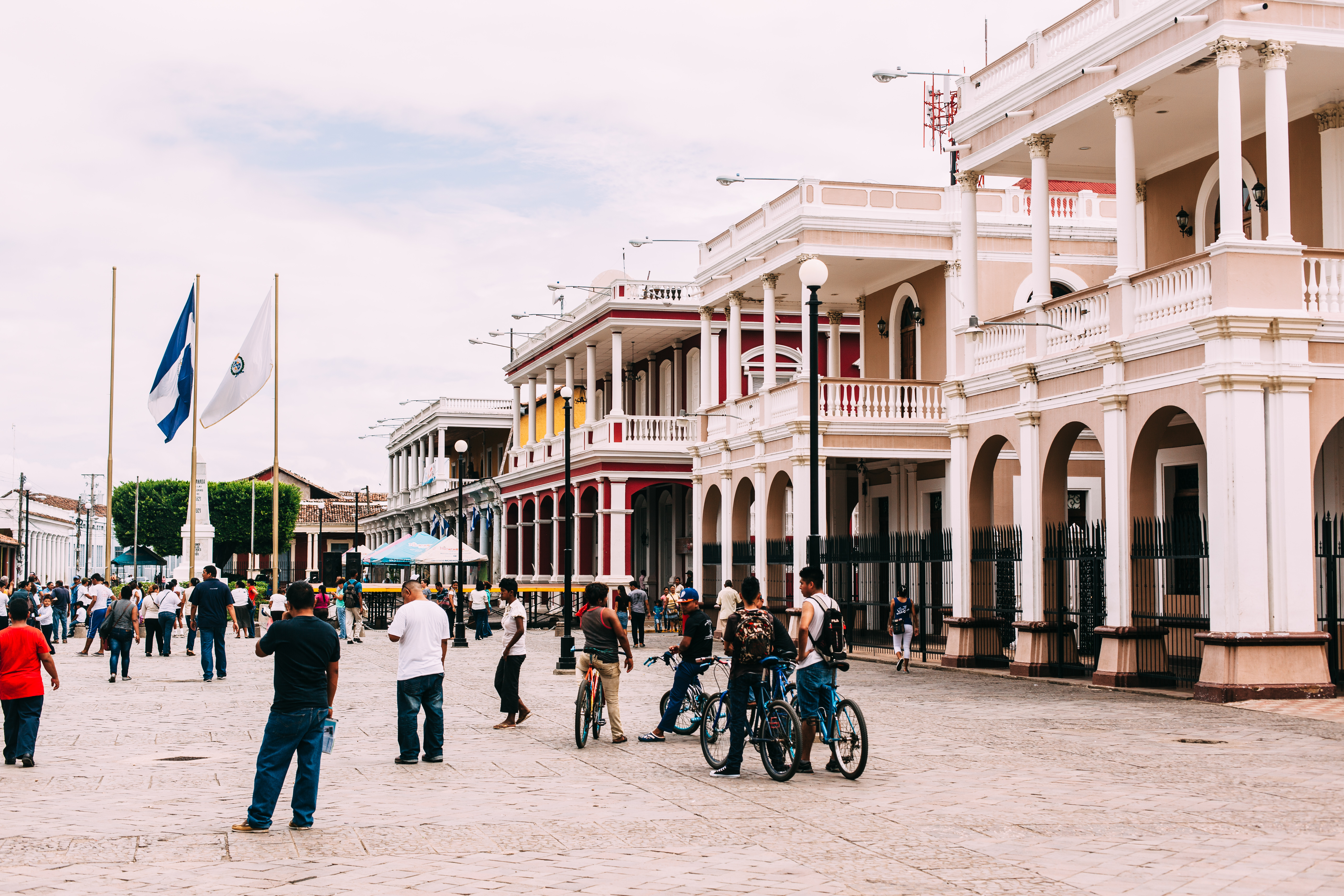 Parque Central plaza in Granada, Nicaragua with pedestrians, cyclists, and neoclassical arcade buildings.