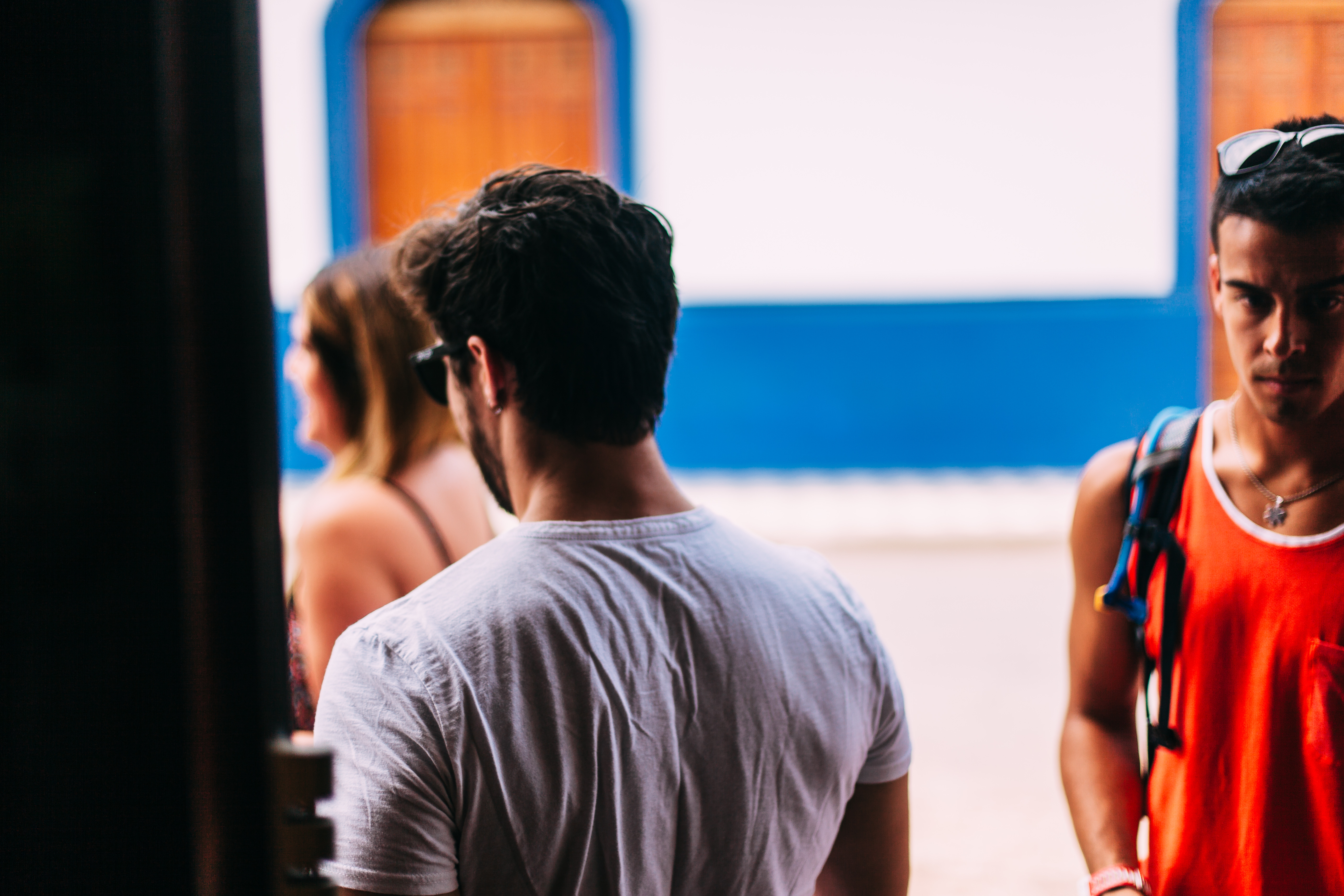 Three friends gathered near an open doorway along a sunlit street in Granada, Nicaragua.