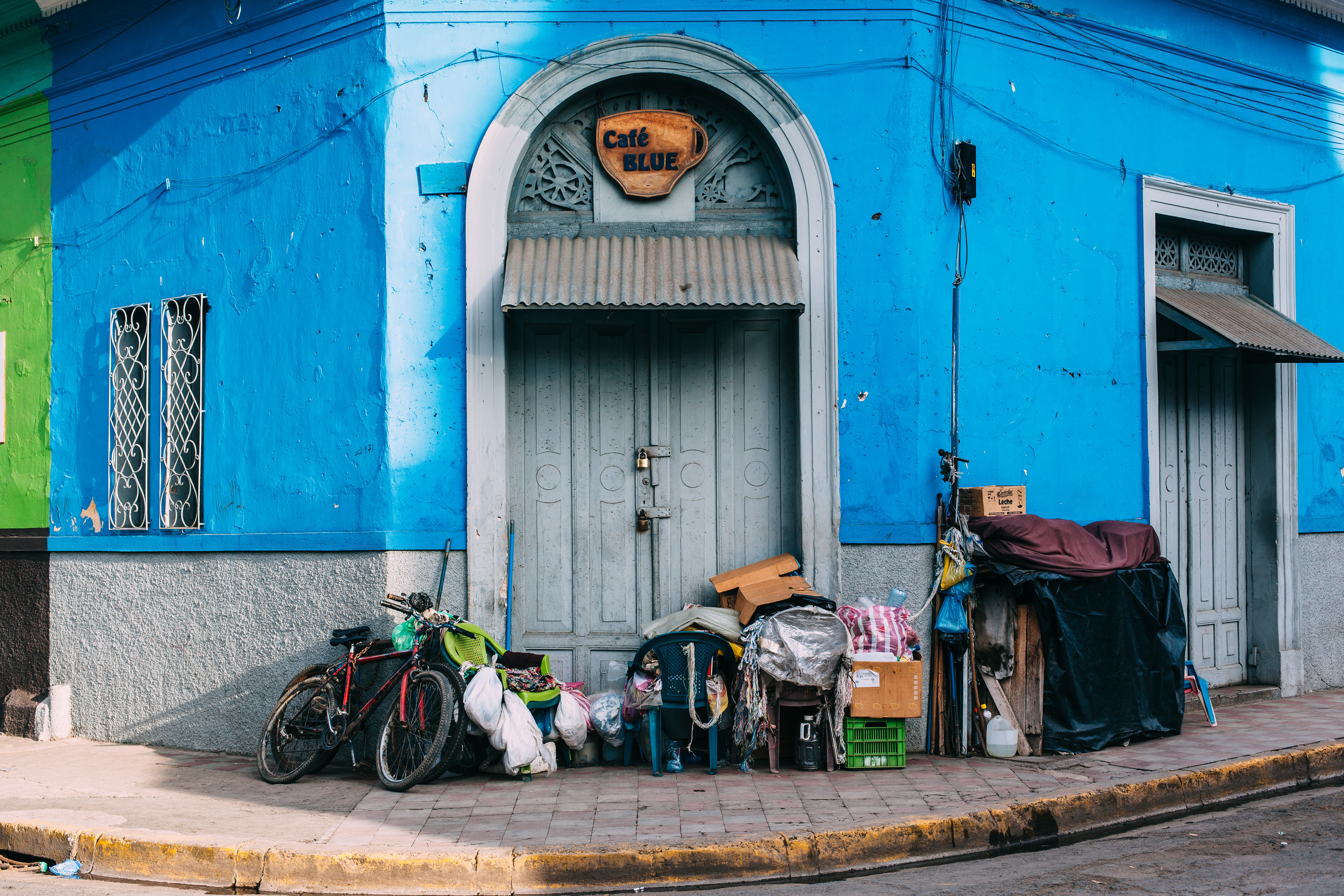 Cobalt blue building in Granada, Nicaragua with 'Café Blue' sign, bicycles, and chairs outside doorway.