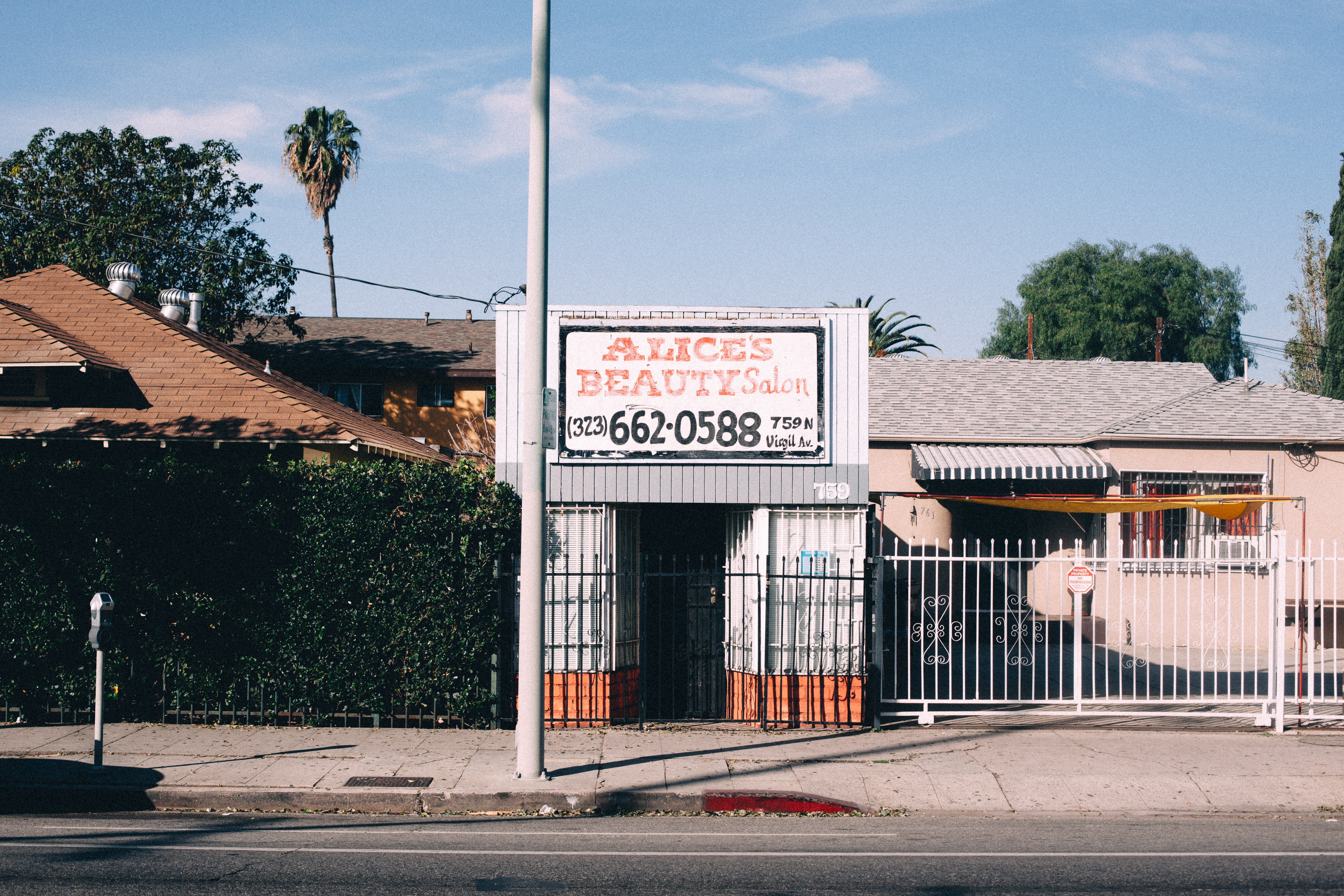 Street view of Alice's Beauty Salon storefront at 759 N Virgil Avenue with a painted sign, security gate, and a palm tree behind under a clear blue sky, shot with a Canon 5D Mark II.