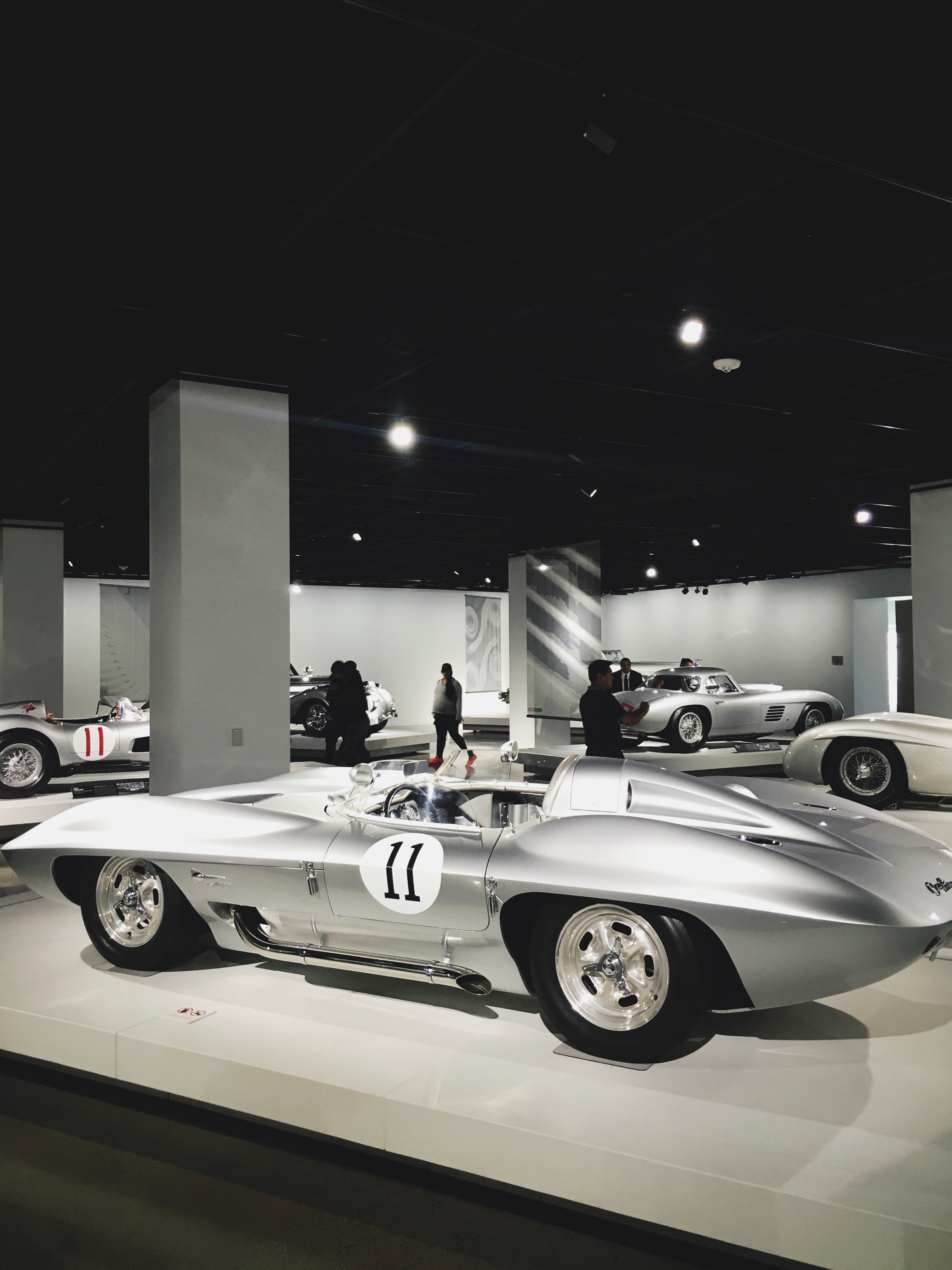Sleek silver 1959 Corvette Stingray Racer concept car bearing number 11 in a darkened museum gallery.