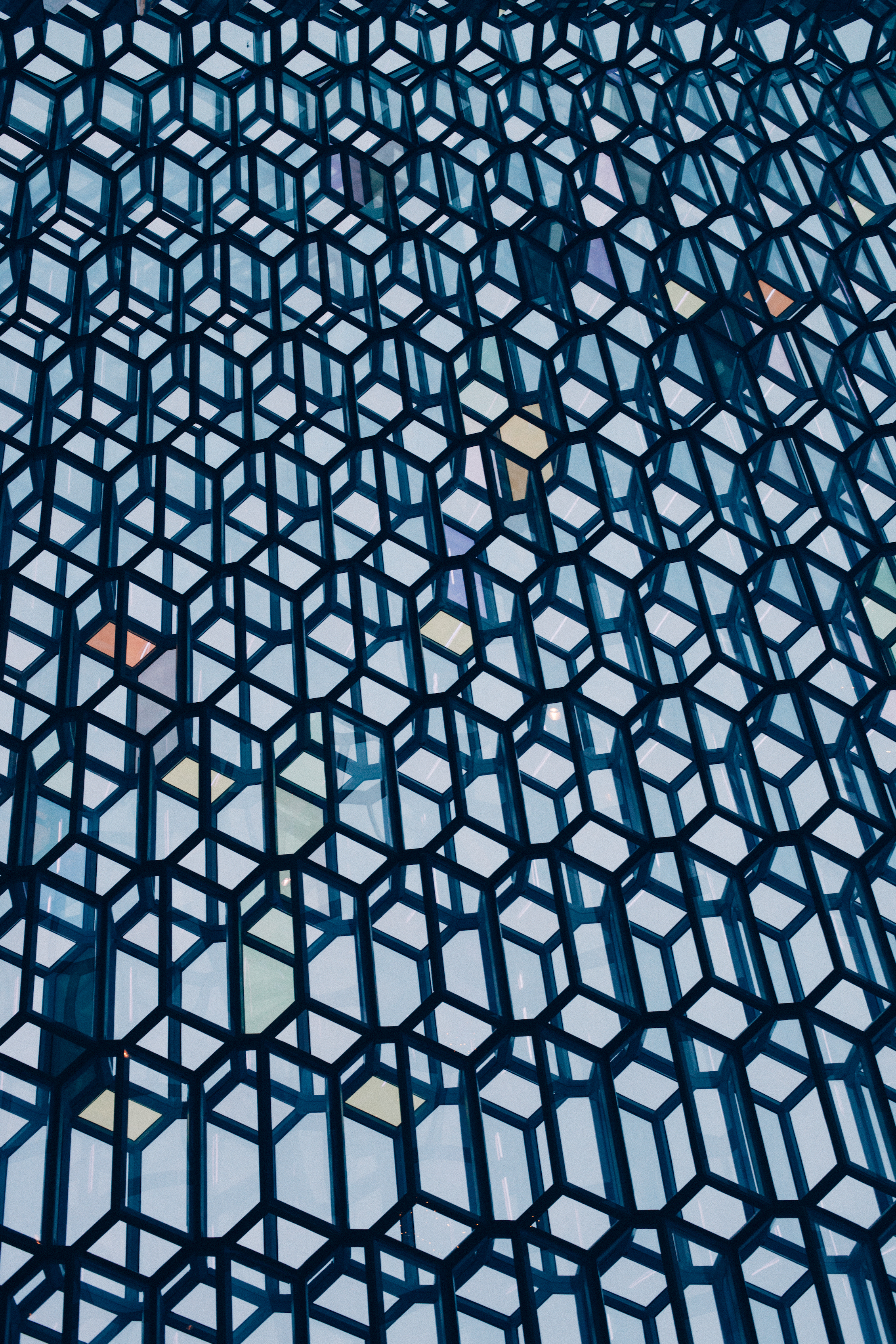 Honeycomb glass facade of Harpa Concert Hall with colored glass panels against sky in Reykjavik.