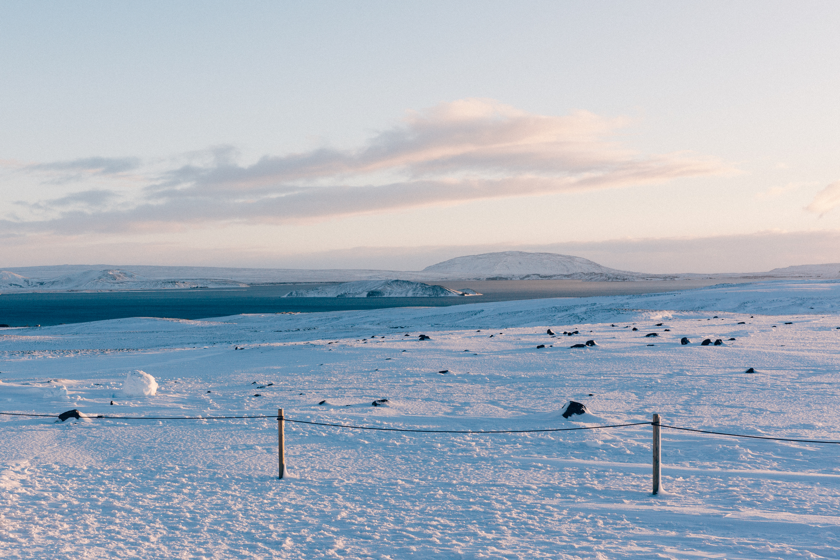 Rope fence overlooking icy blue waters of Lake Thingvallavatn and volcanic mountains in Iceland.
