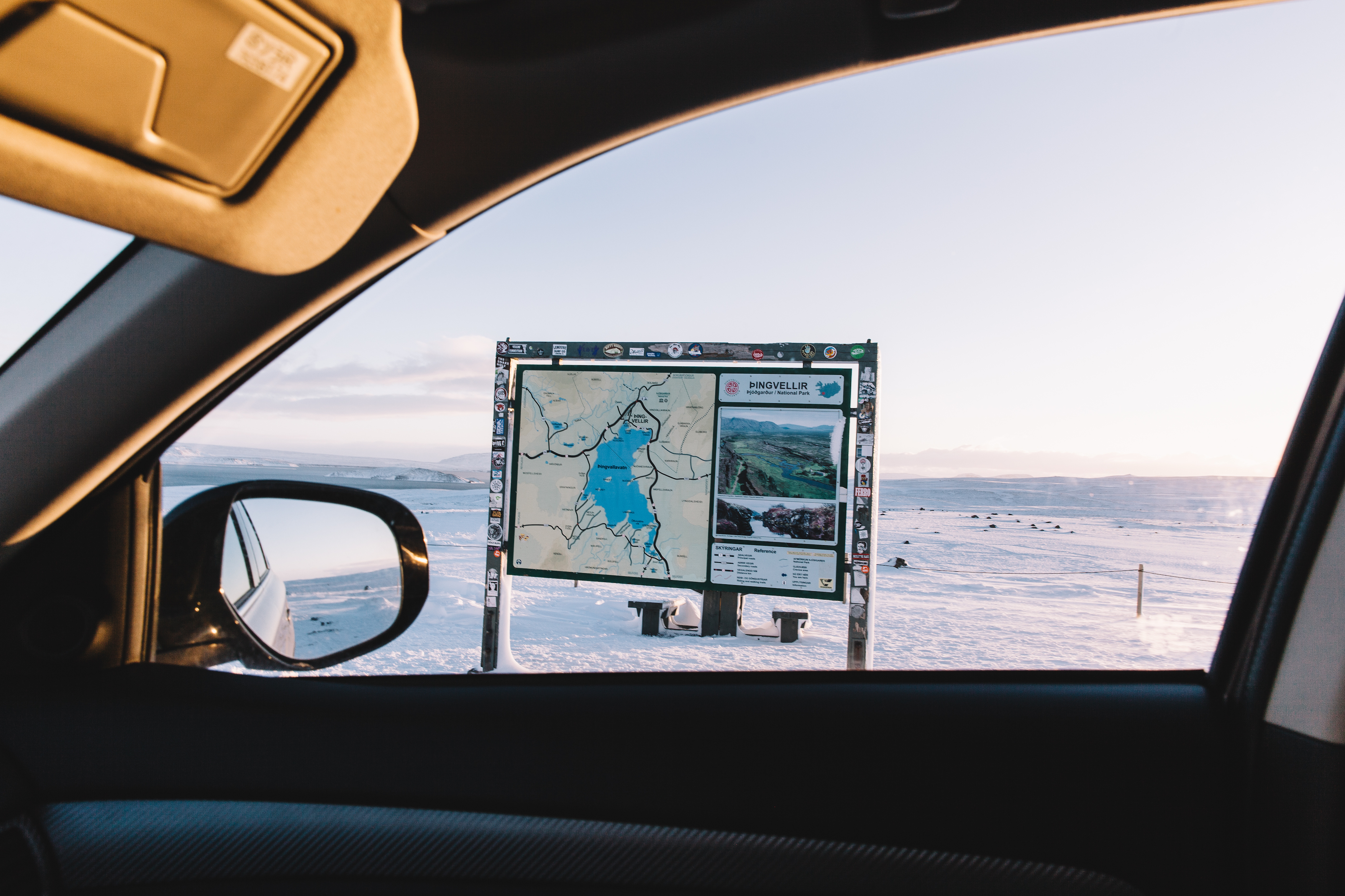 View through a car window of an informational trail and park map sign for Þingvellir National Park in Iceland.