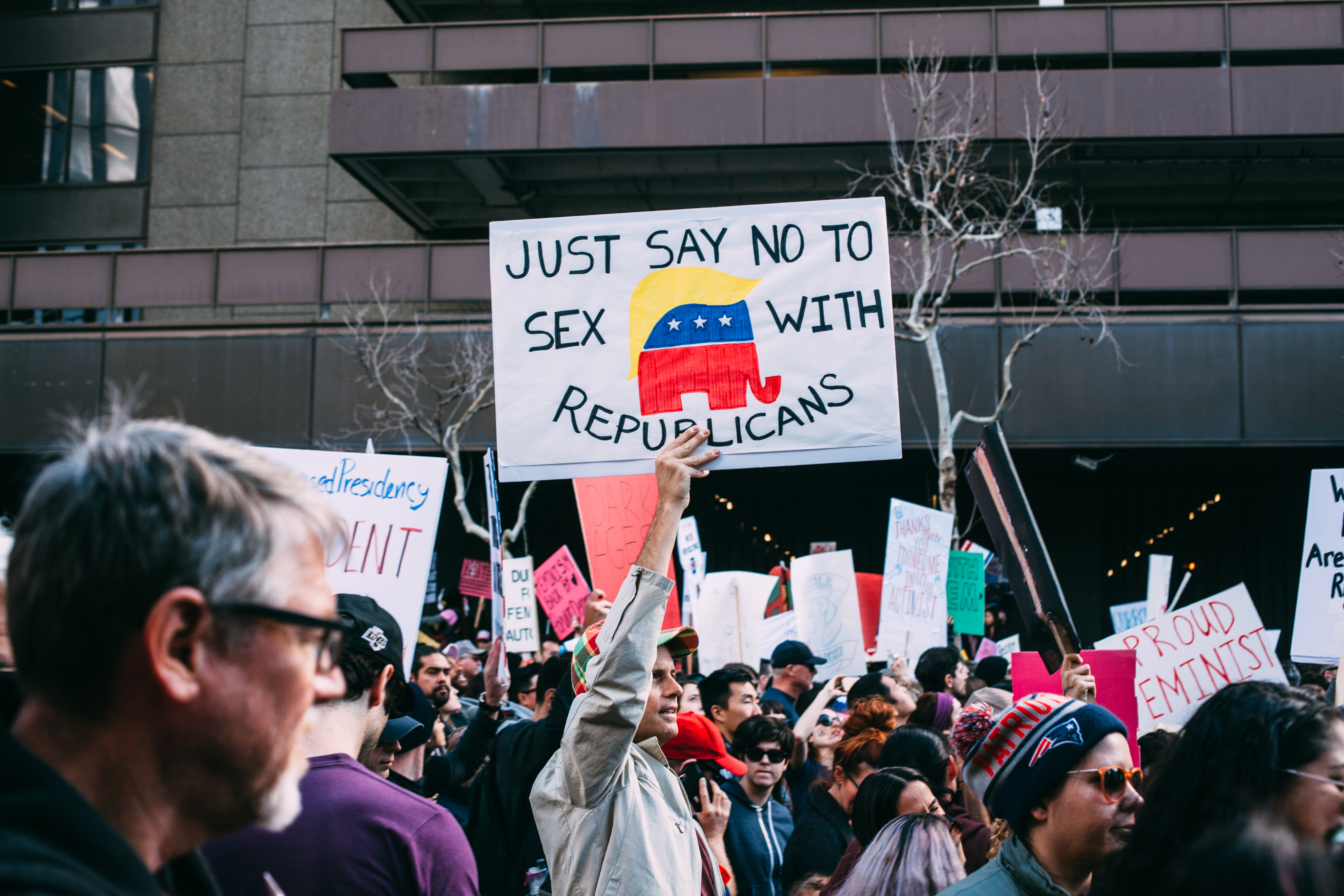 A demonstrator holding up a political protest sign reading 'Just say no to sex with Republicans' surrounded by crowds of people at the Women's March in Los Angeles, shot with a Canon 5D Mark II.
