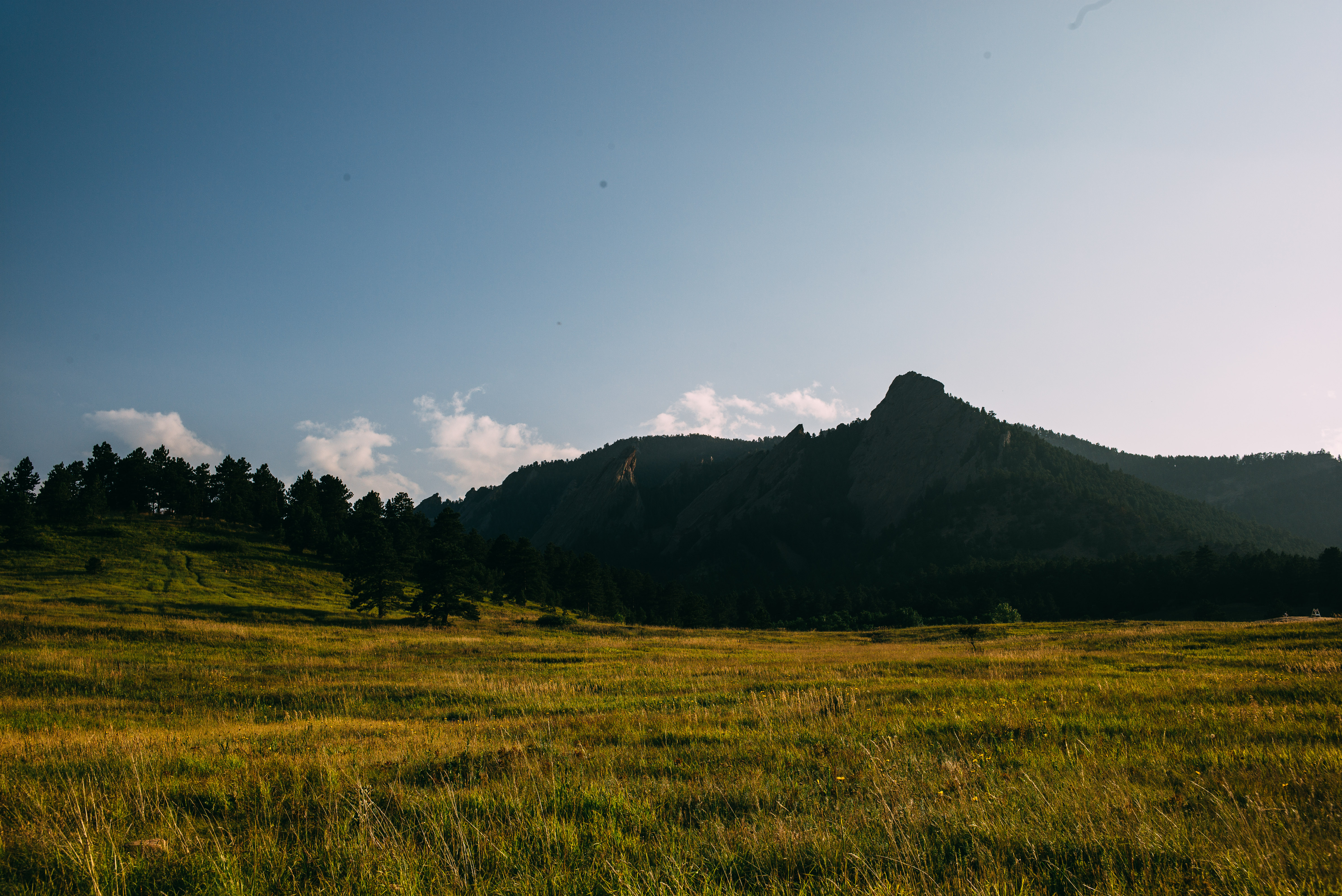 Golden meadow looking toward the rugged Flatirons rock formations under an afternoon sky in Boulder.