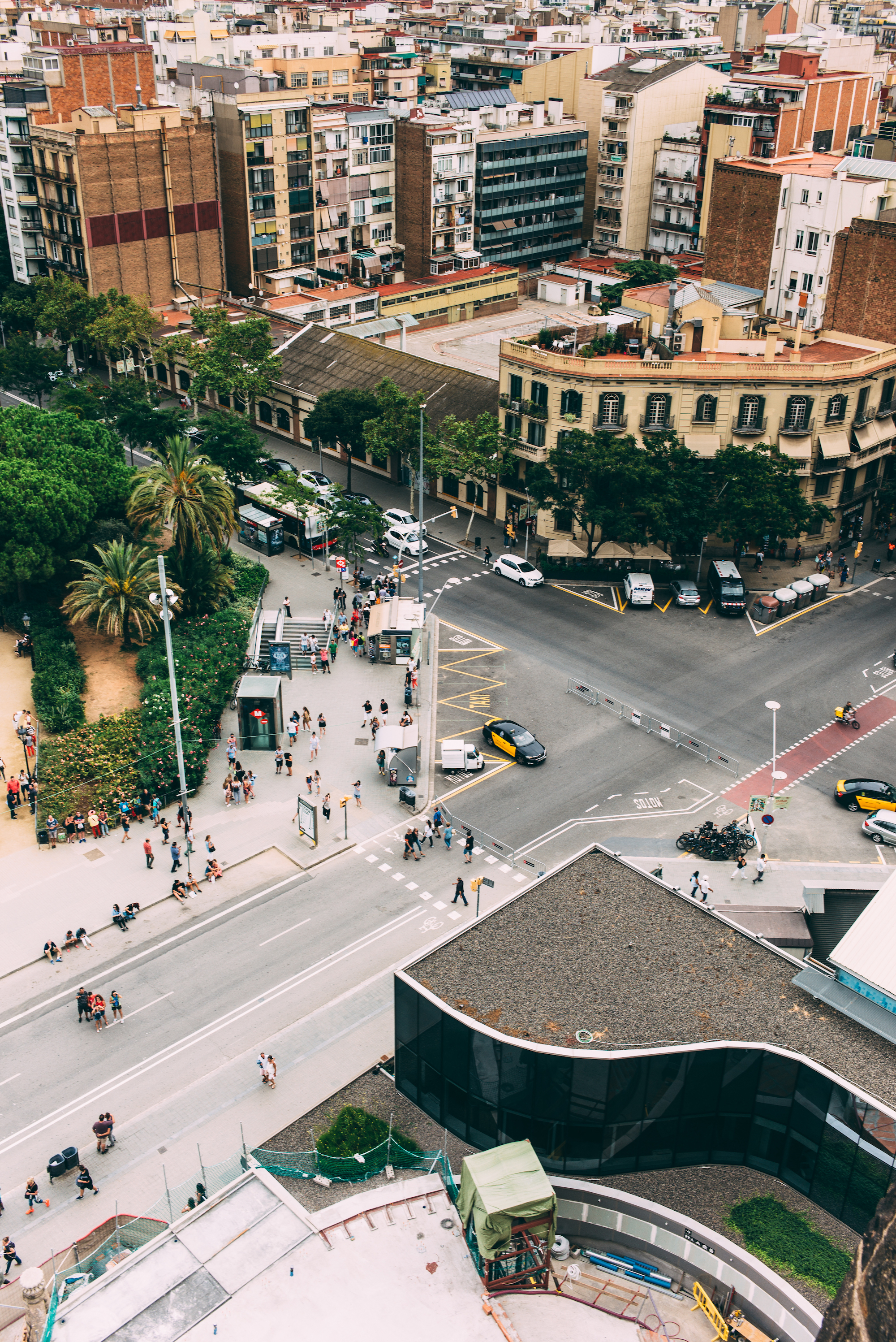 Overhead view of a bustling Barcelona street intersection with crosswalks, yellow taxis, and apartment blocks.