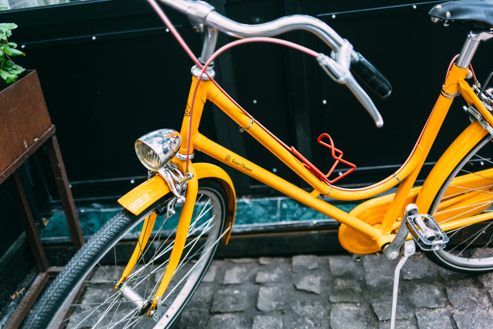 Yellow Veuve Clicquot cruiser bicycle with chrome headlamp and leather saddle on a Madrid cobblestone street.