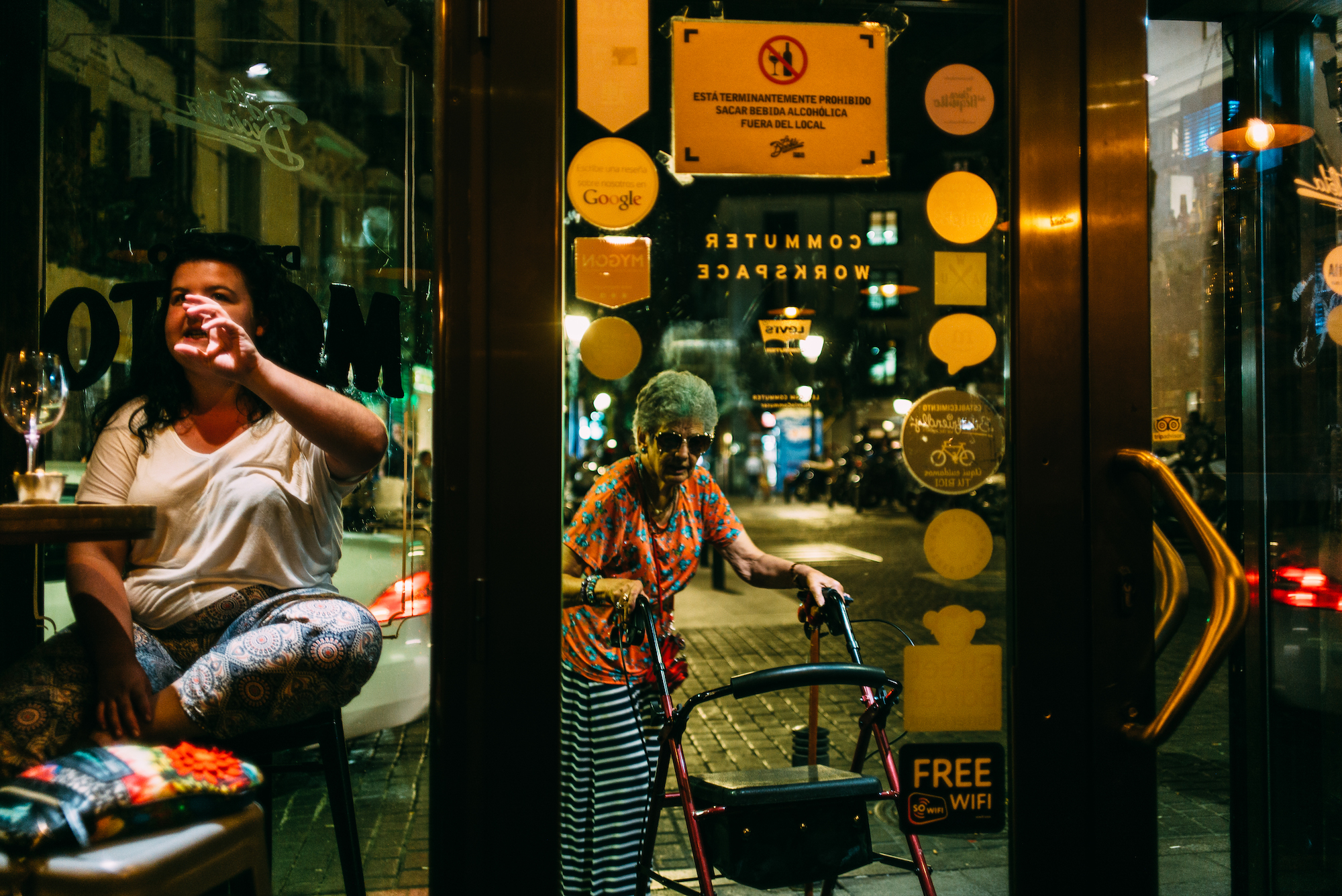Elderly woman with a walker passing outside the window counter of La Bicicleta Cafe in Madrid.