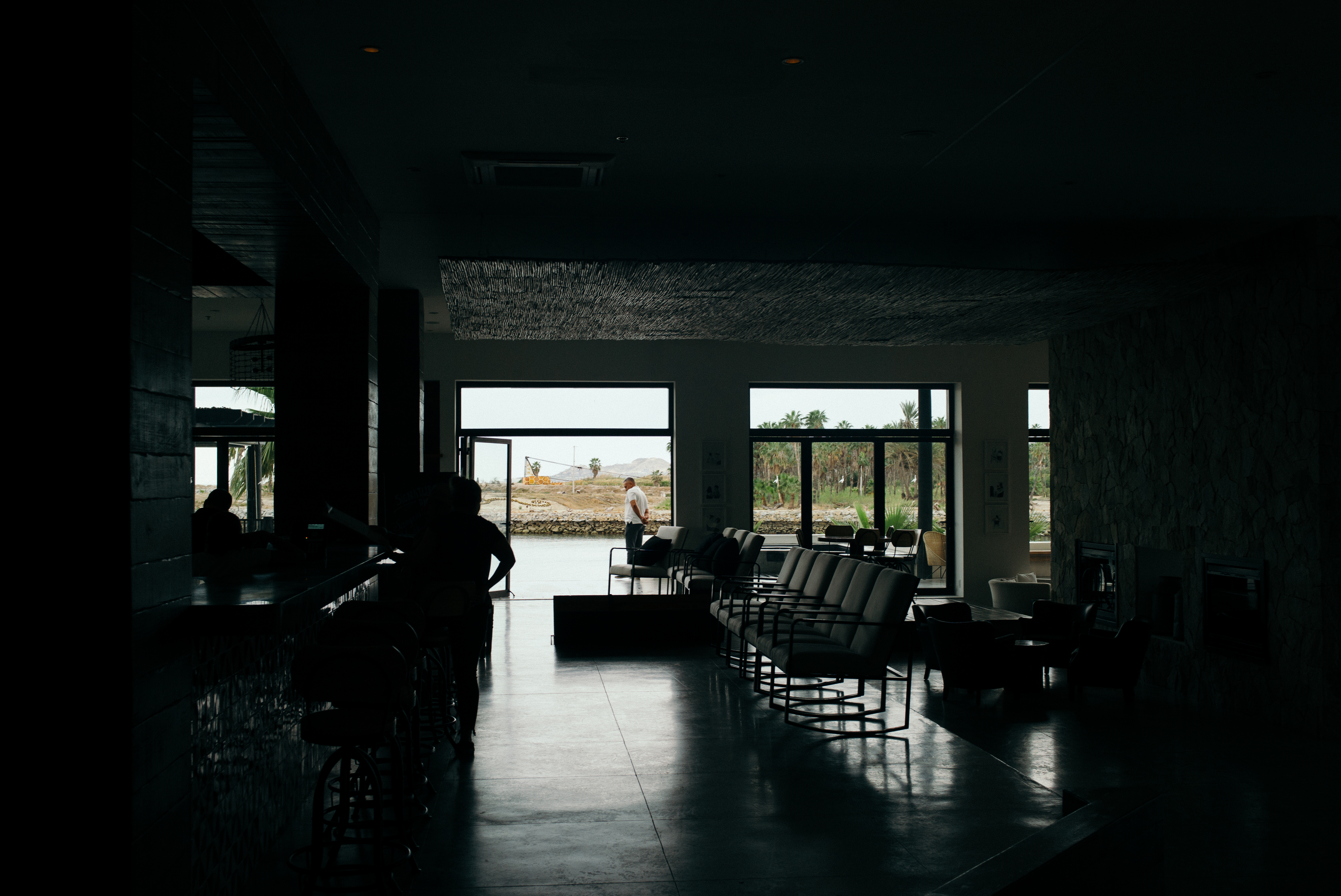 Guests relaxing on sun loungers on a wooden sundeck beside a rooftop infinity pool overlooking yachts moored in the marina in San Jose del Cabo, shot with a Leica M240.