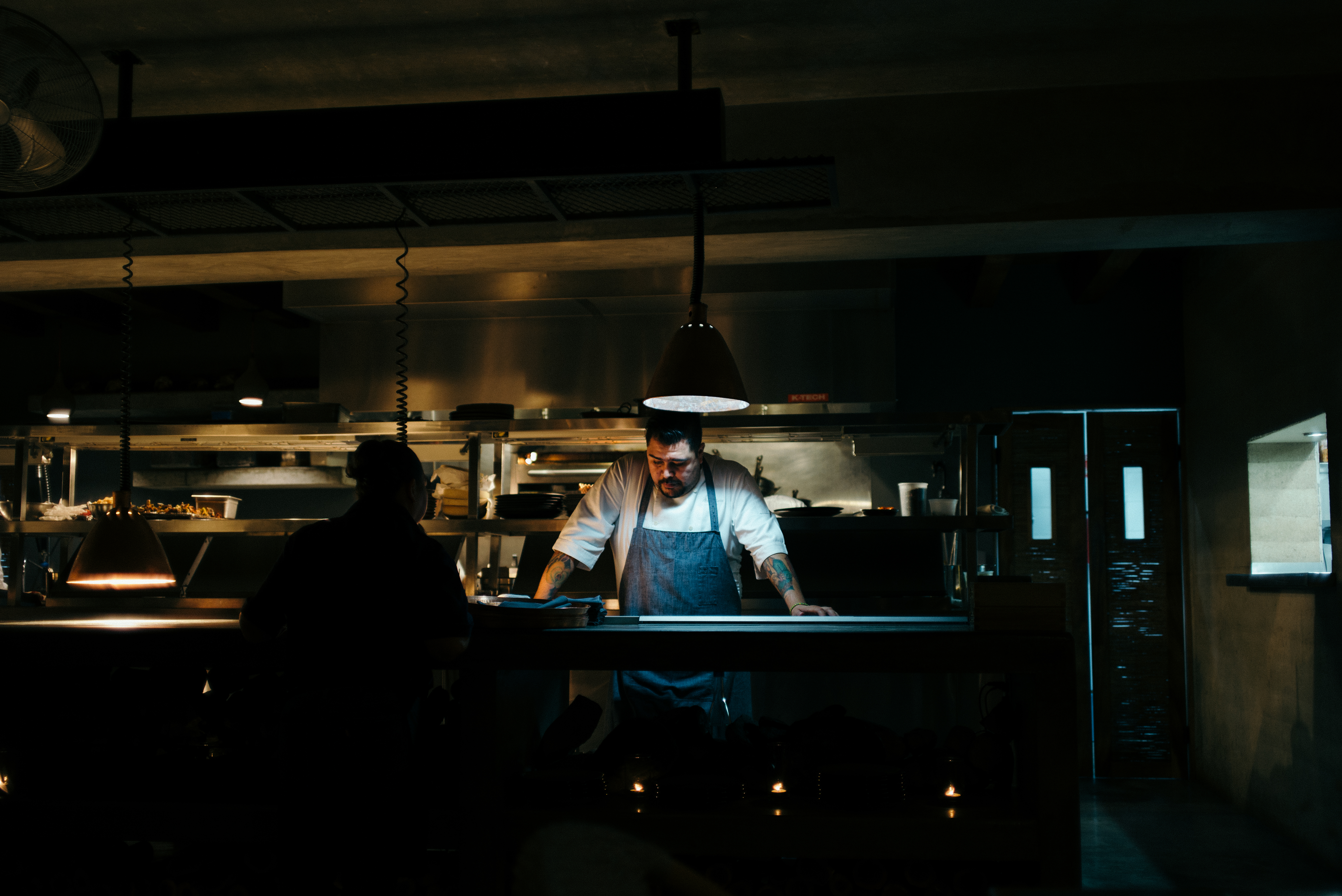 Chefs and kitchen staff preparing food on cutting boards in an open restaurant kitchen in San Jose del Cabo.