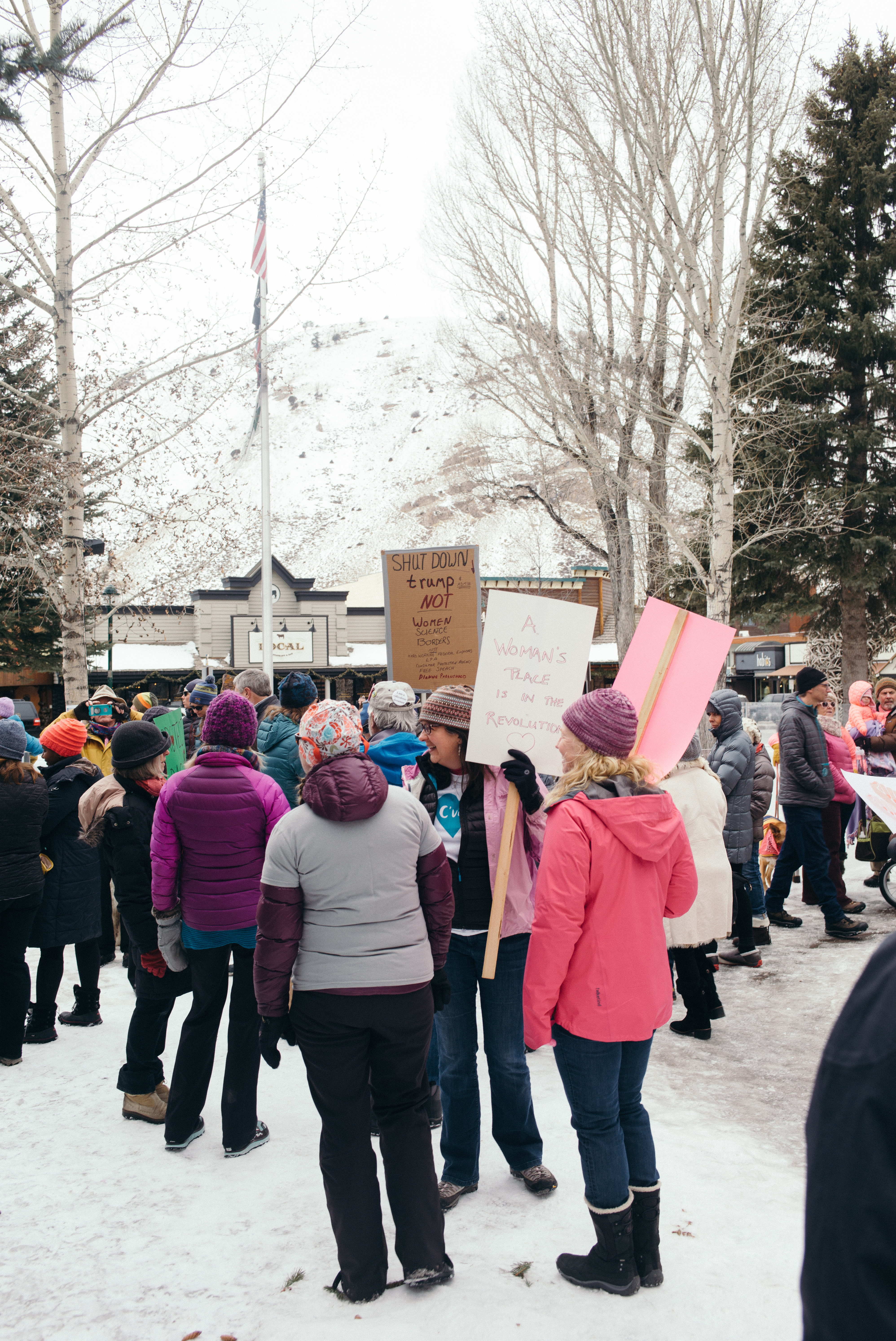 Demonstrators holding signs reading 'A Woman's Place is in the Revolution' and 'Shut down Trump not women'.