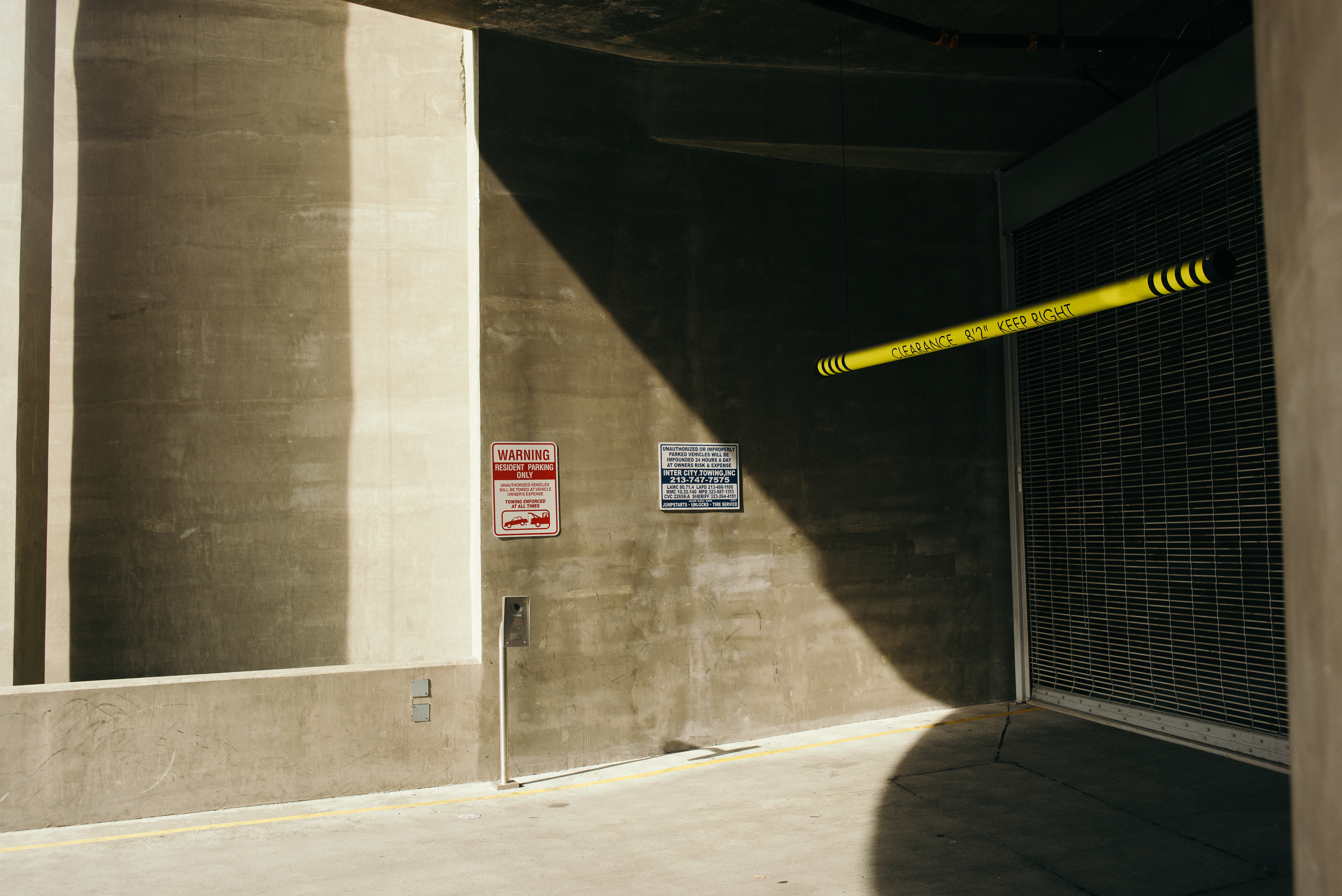 Parking garage entrance with a clearance bar reading 'CLEARANCE 8'2" KEEP RIGHT' and tow signs.