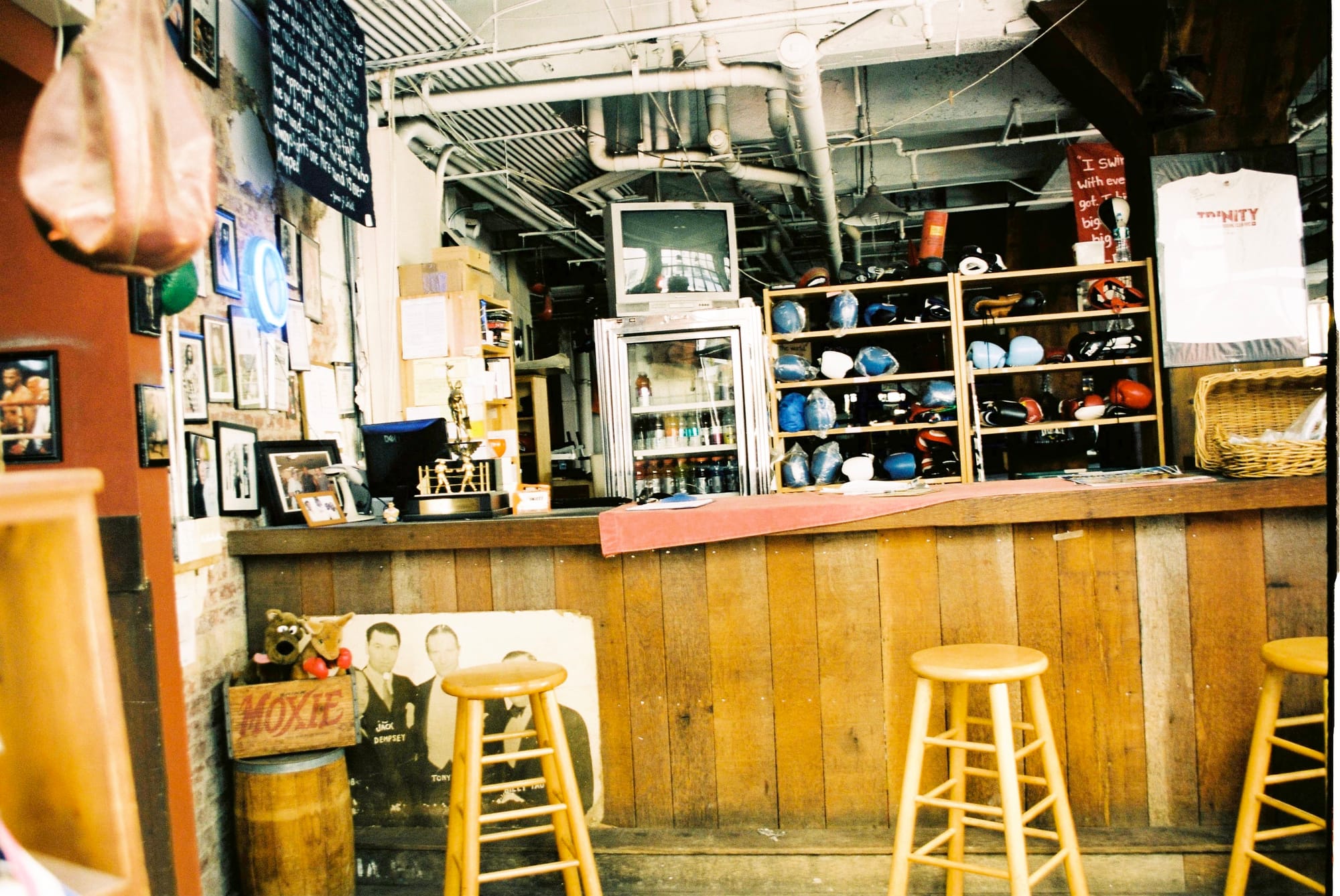 Interior of Trinity Boxing Club in New York City with counter stools, trophies, and shelves of gloves.