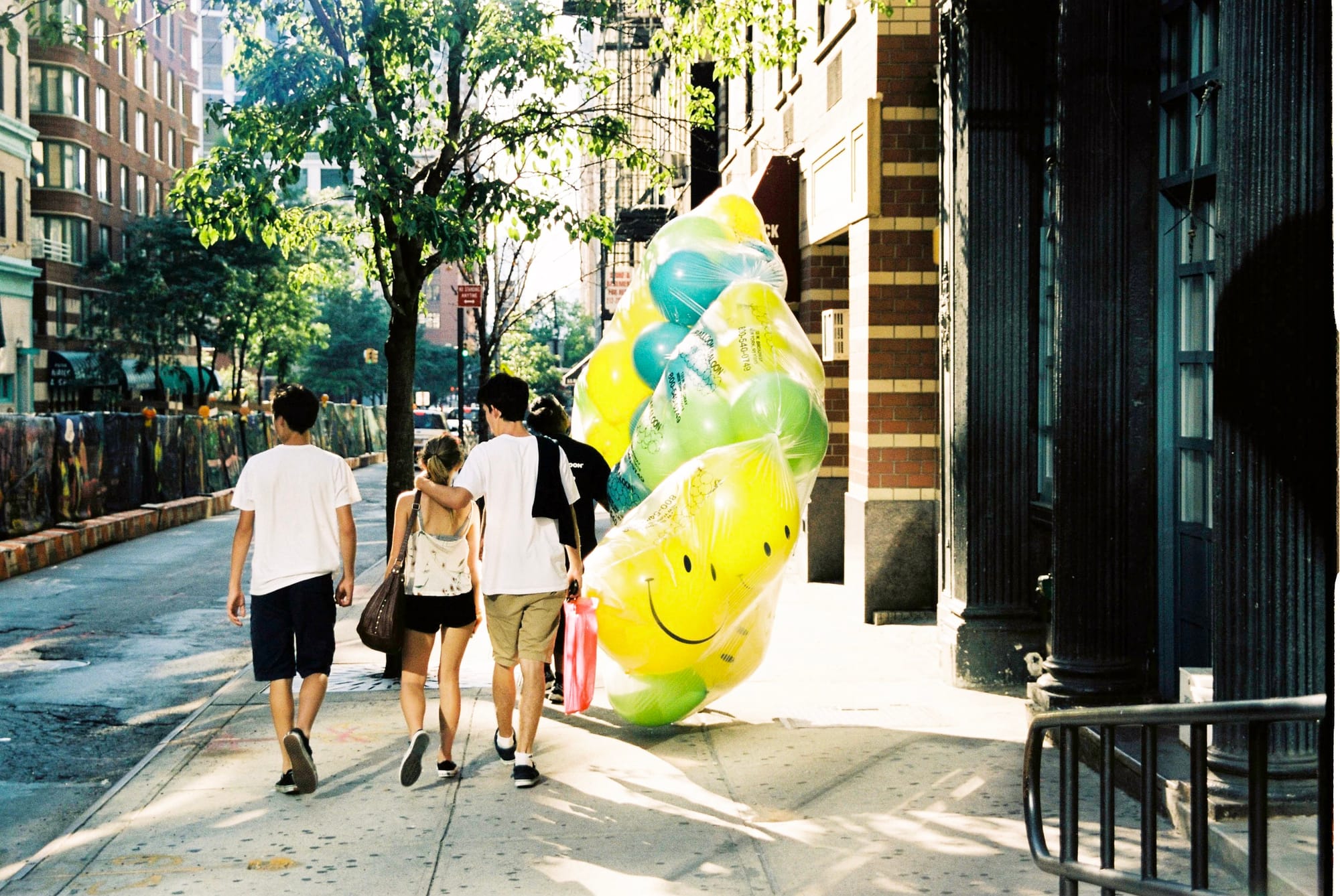 Pedestrians strolling along the sunlit sidewalks of downtown New York City.