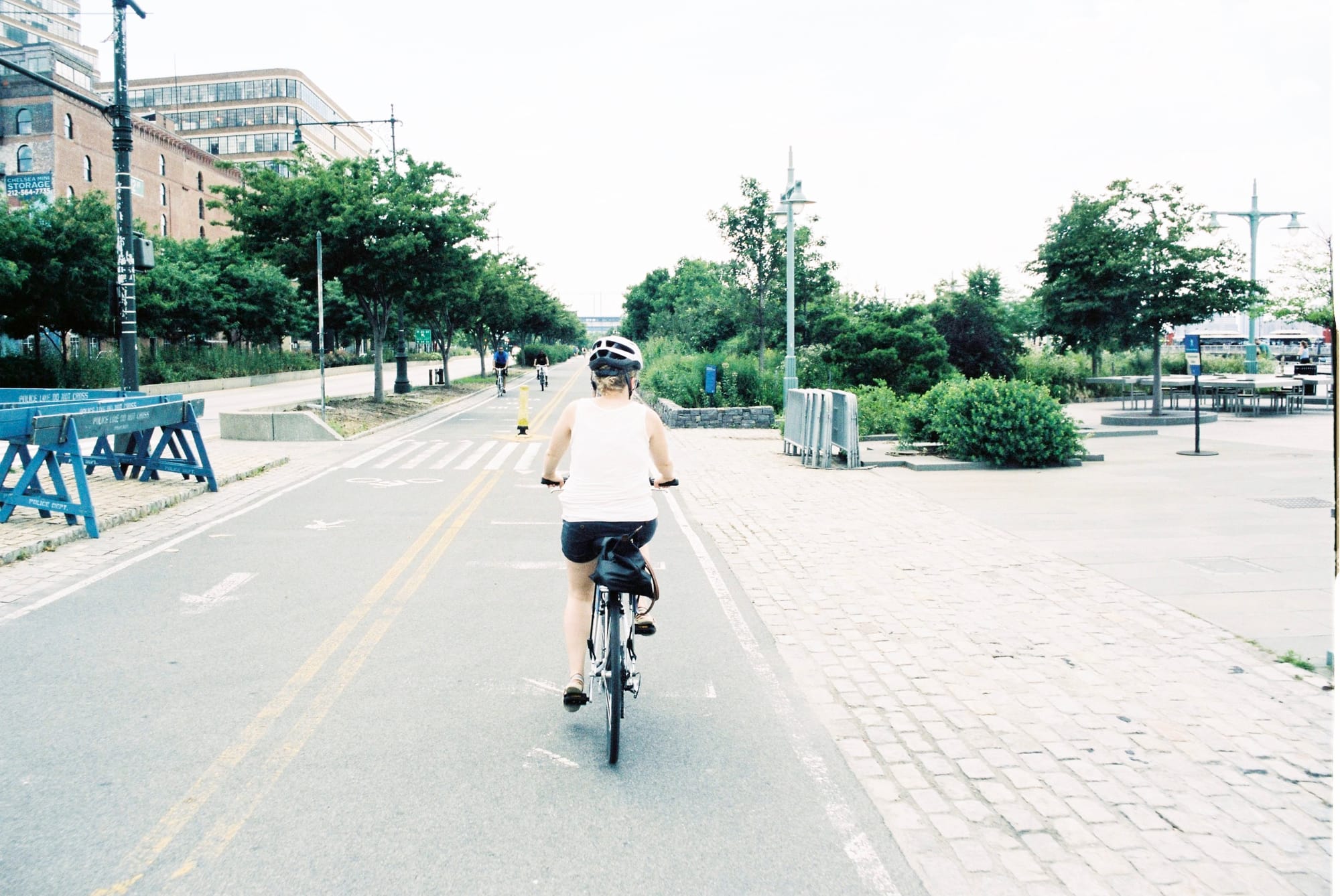 Caitlin riding her bicycle along a sunny tree-lined street in Lower Manhattan.