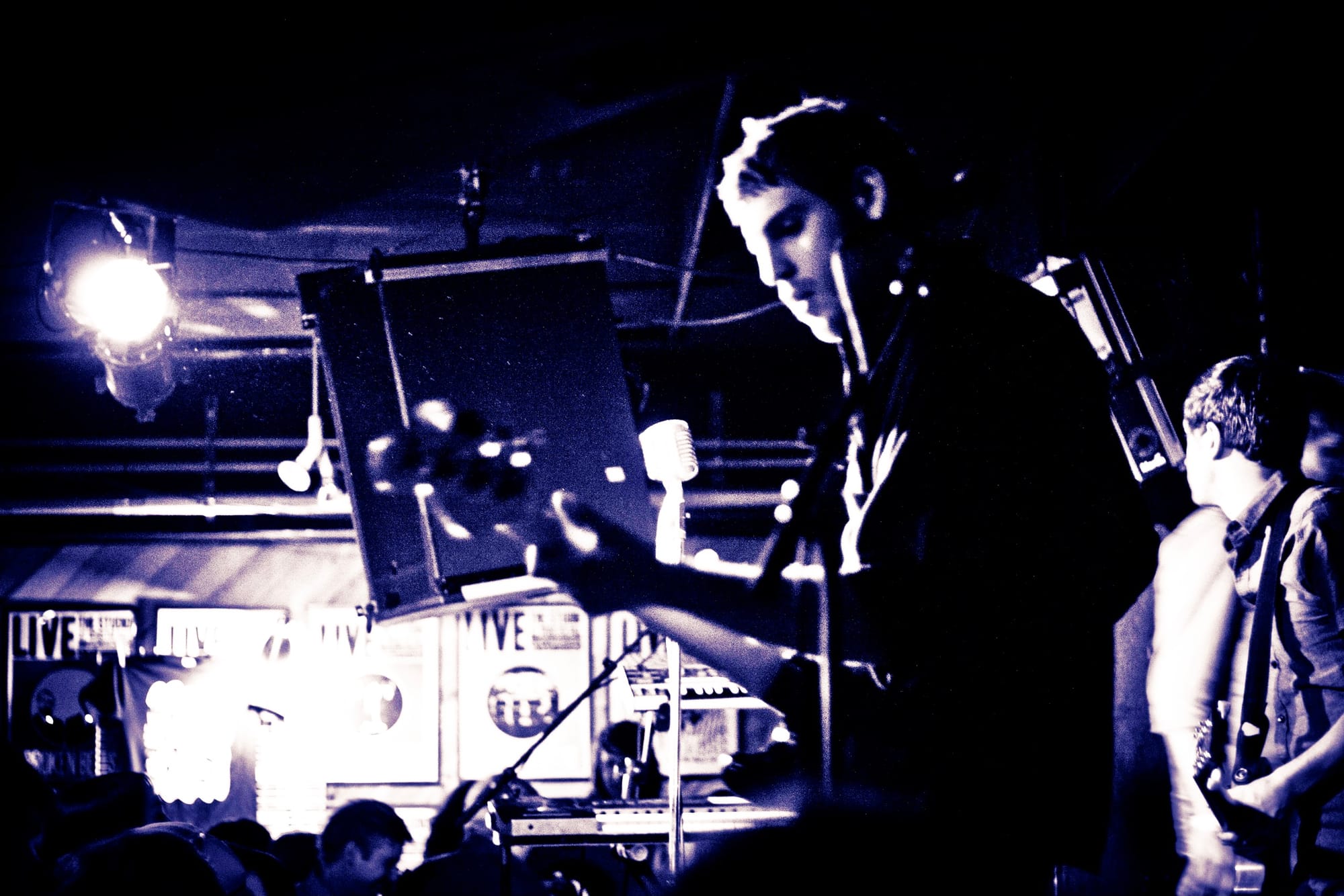 Guitar effects pedals and tangled audio cables across the wooden stage floor at a concert.