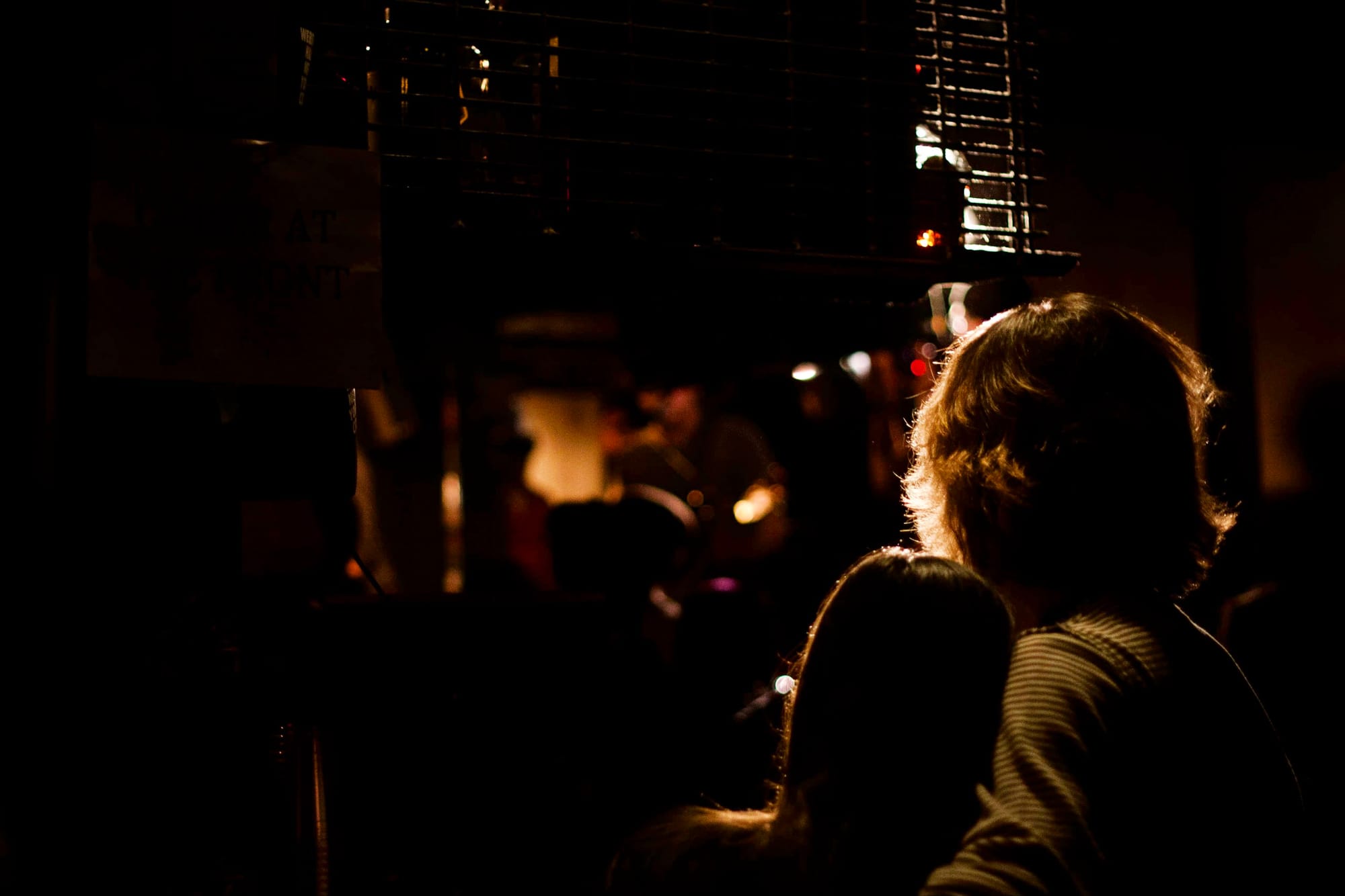 Dimly lit music venue seen past performers on stage.