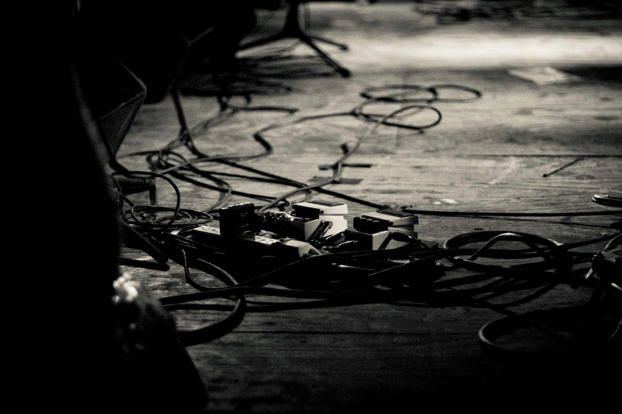 Musician playing bass next to a pillar catching the shadow of the guitar headstock and tuning pegs.