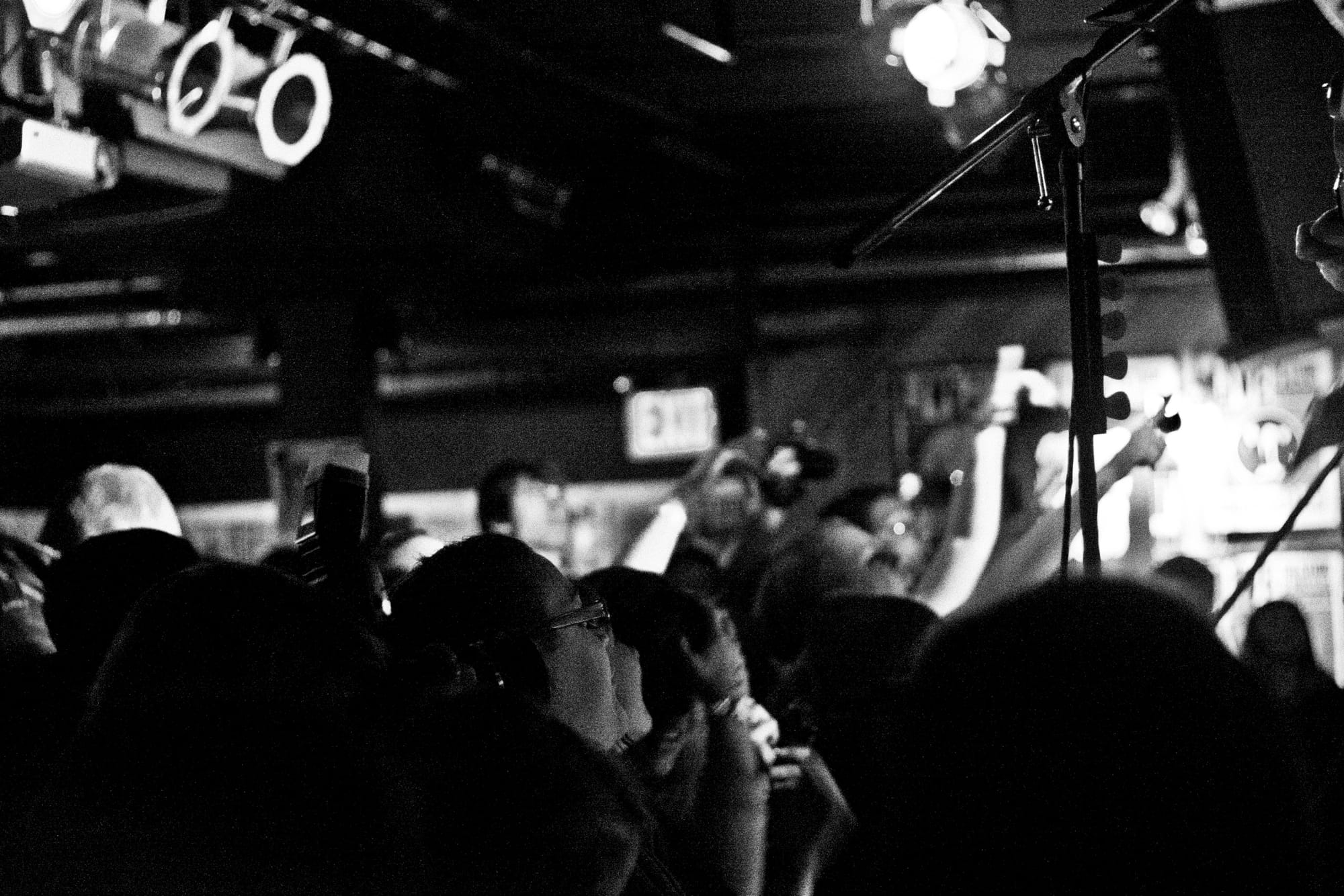 Energized concert crowd packed close to the stage looking up toward performers under spotlights.