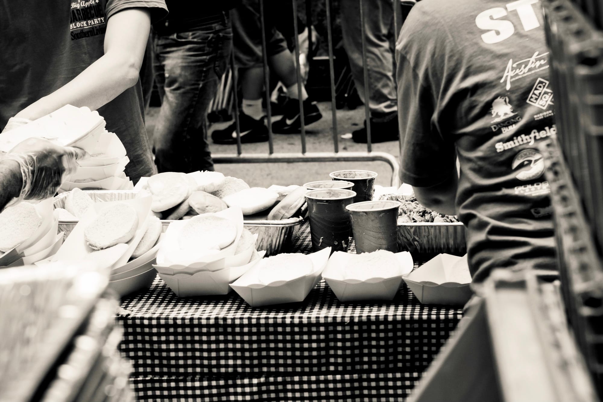 Close-up of freshly smoked pulled pork and barbecue ribs being sliced and served at a festival food station.