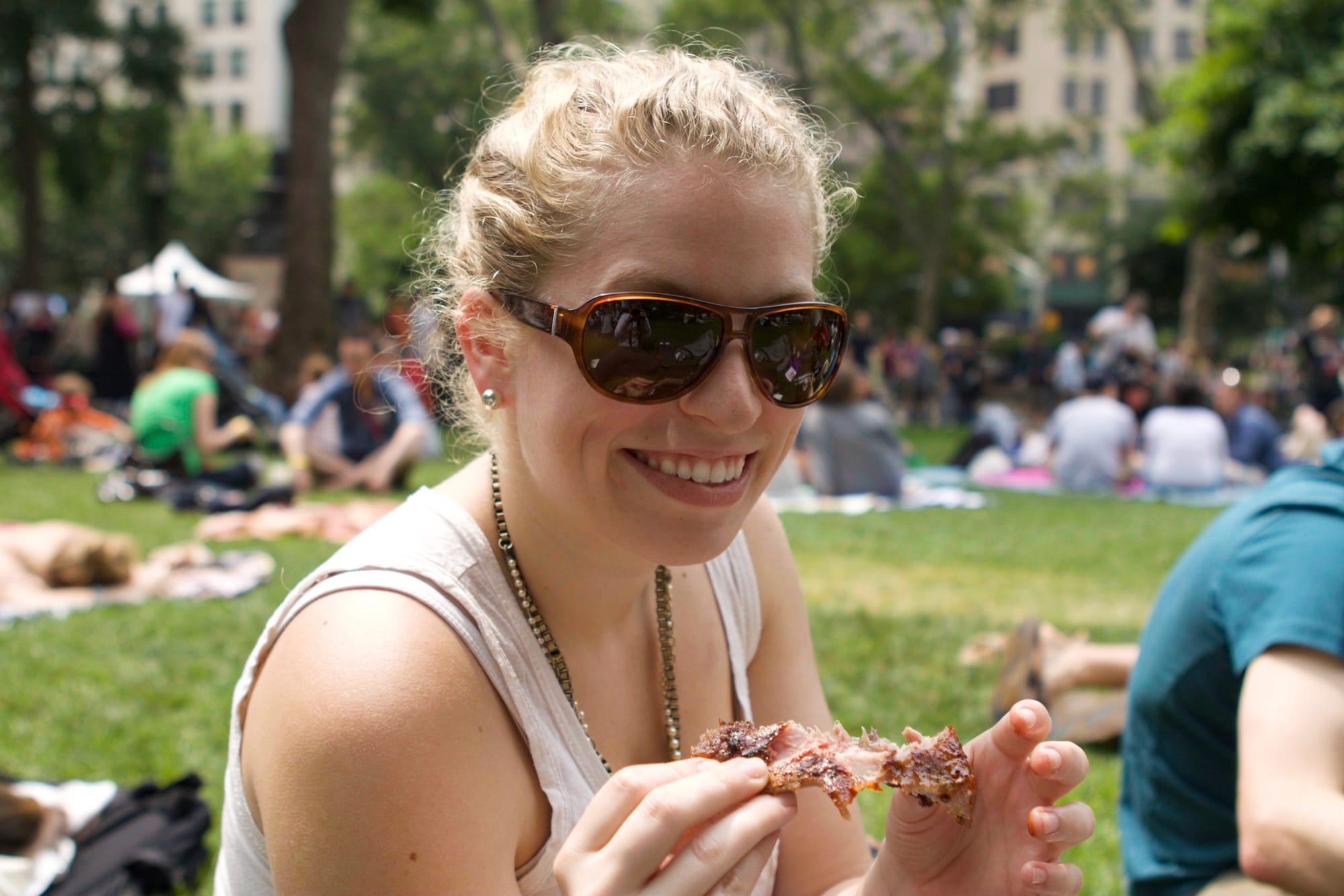 Caitlin and festival attendees enjoying barbecue and cold drinks in the park during the Big Apple BBQ.