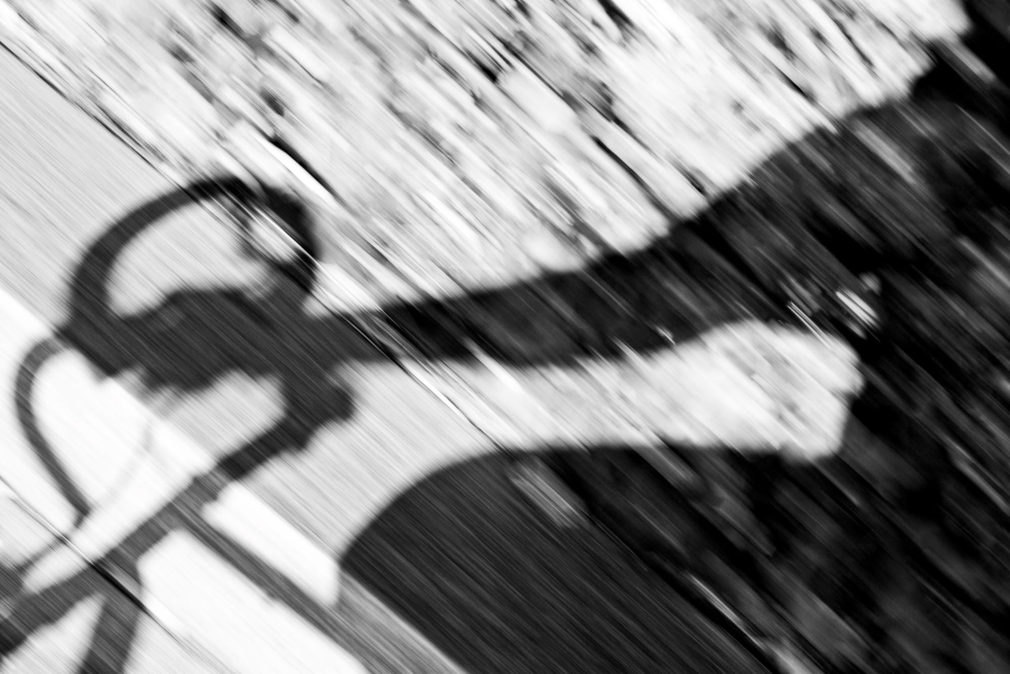 Motion-blur view from a bicycle looking down at pavement with the shadow of drop handlebars and arms.