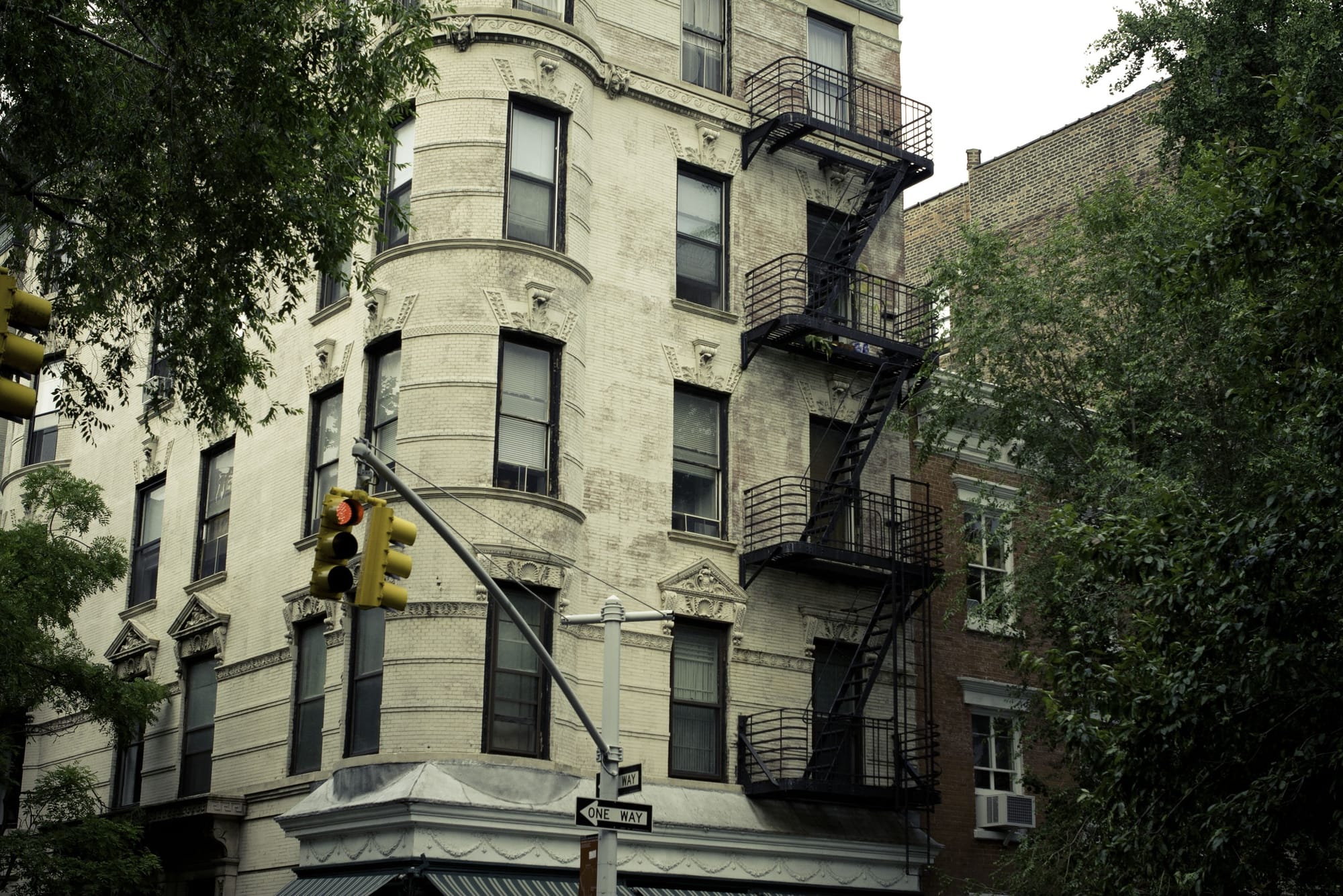 Lush green summer foliage framing neighborhood townhouse architecture in the West Village of Manhattan.