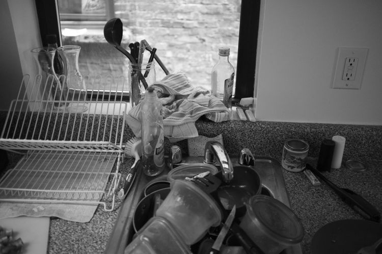 Black and white view of a kitchen counter with a dish rack and drying pots.