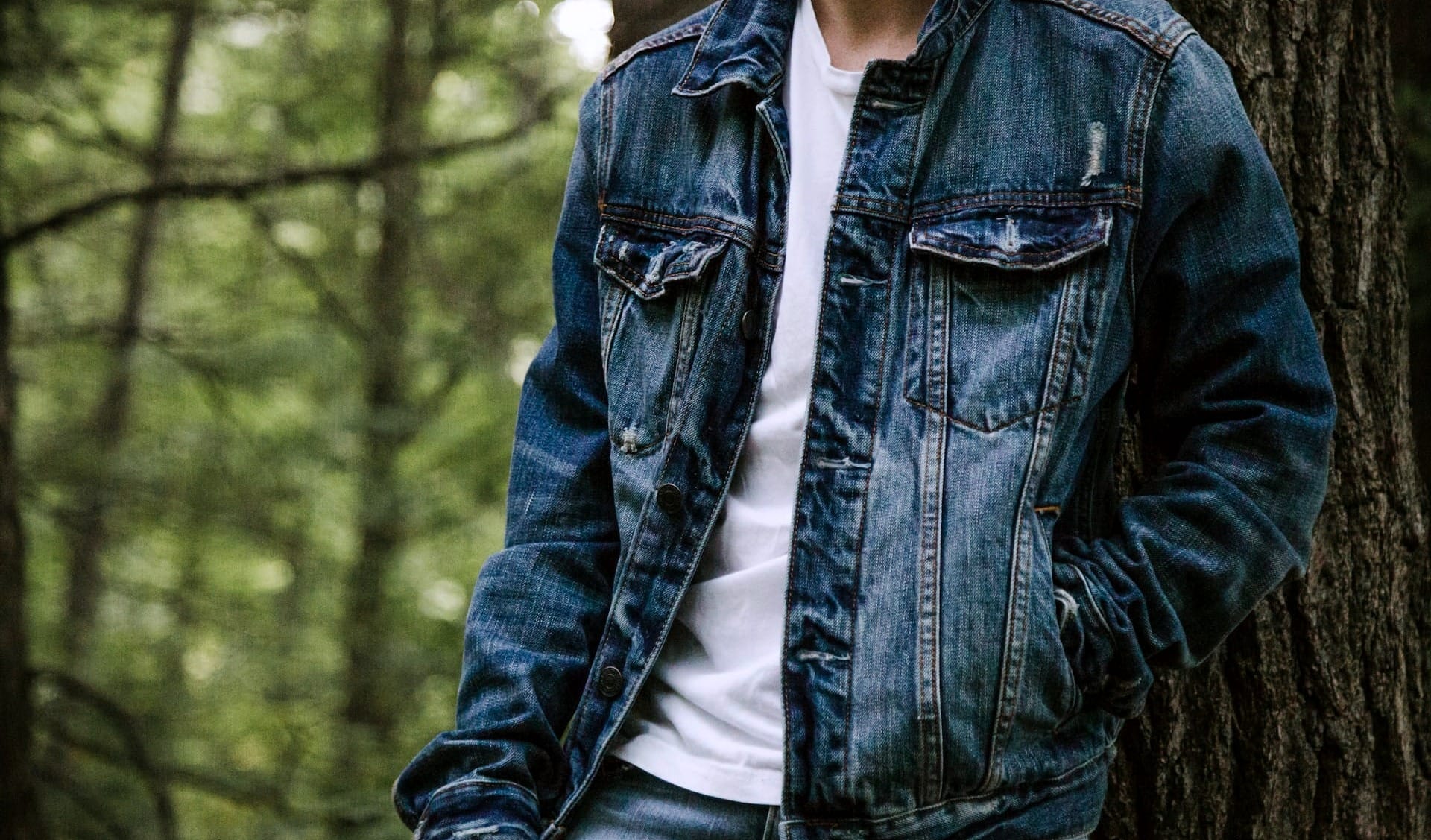 Person trägt eine Jeansjacke im Freien, kombiniert mit einem schlichten weißen T-Shirt