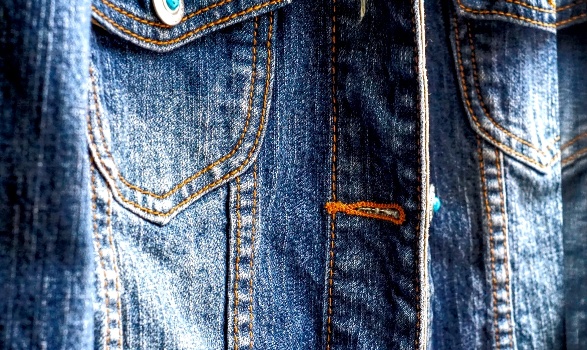 Detailaufnahme einer Jeansjacke mit sichtbaren Nähten und Knopfleiste