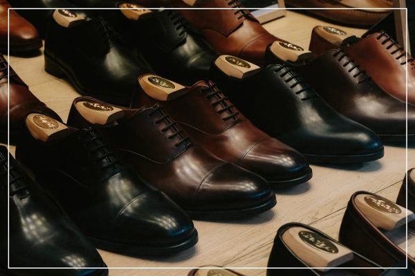 Mehrere klassische Herrenschuhe aus Leder auf einem Tisch, darunter schwarze und braune Oxford- und Derby-Schnürschuhe mit Schuhspannern.