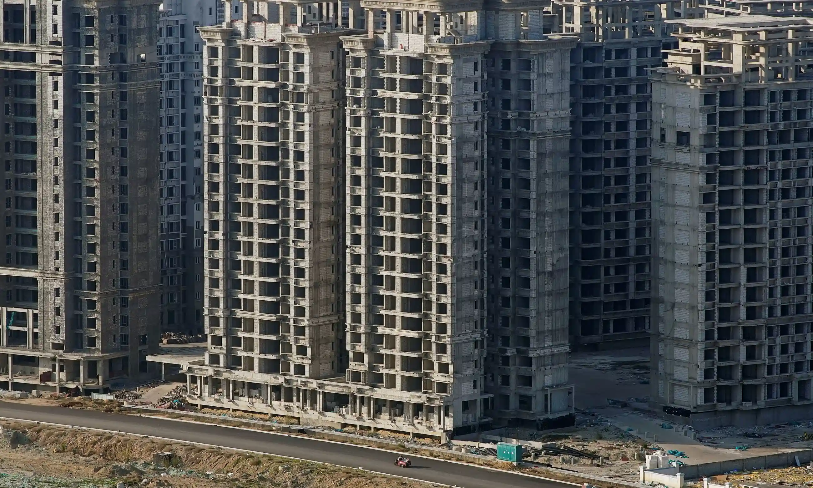 A vehicle travels passes unfinished tower blocks in Danzhou, Hainan province. The development by the Evergrande Group is subject to a demolition order. Photograph: Aly Song/Reuters