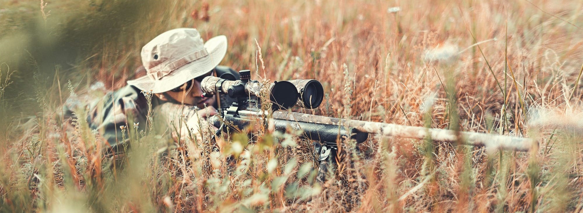 man in brown jacket and black pants sitting on brown grass field during daytime