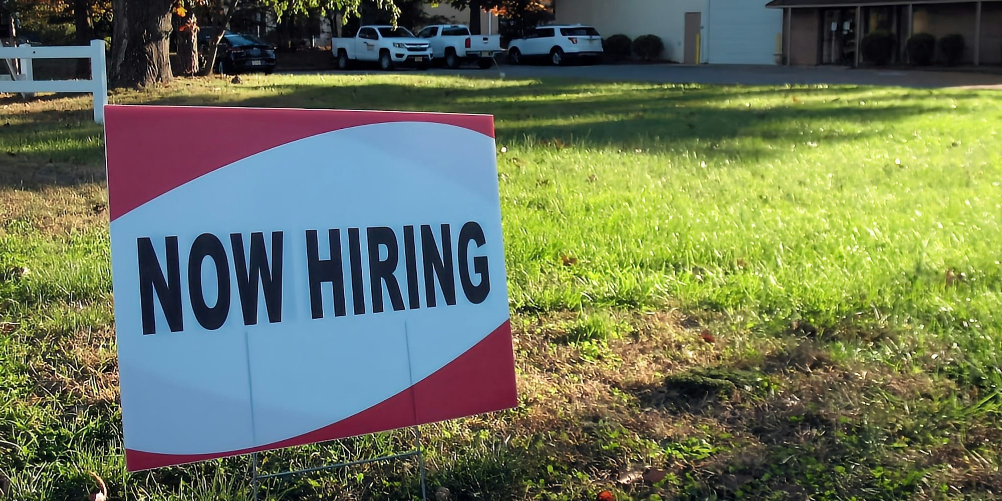 a now hiring sign in front of a building