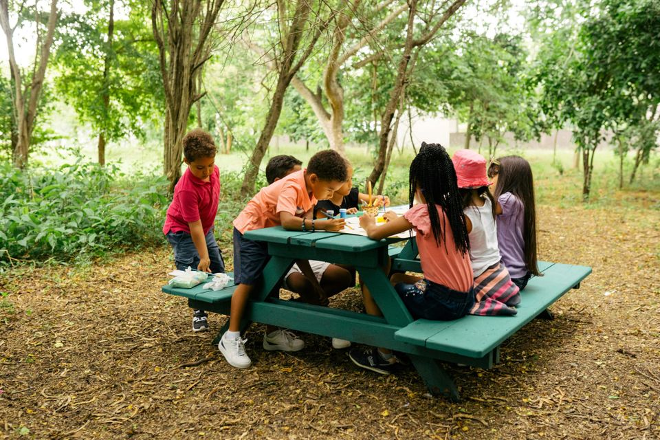 Students gathering a picnic table doing a painting craft.
