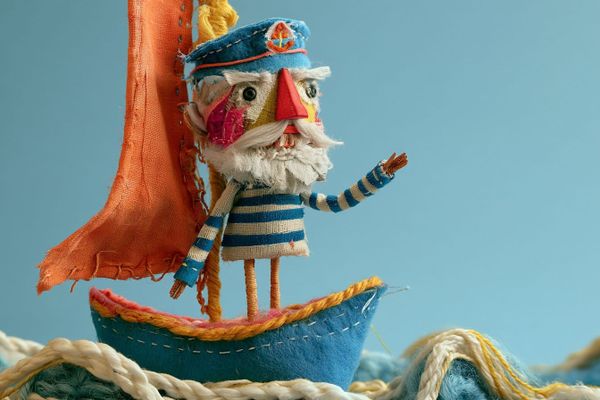 布料船長站在拼布船上，毛線與縫線構成微型場景的 AI 插畫