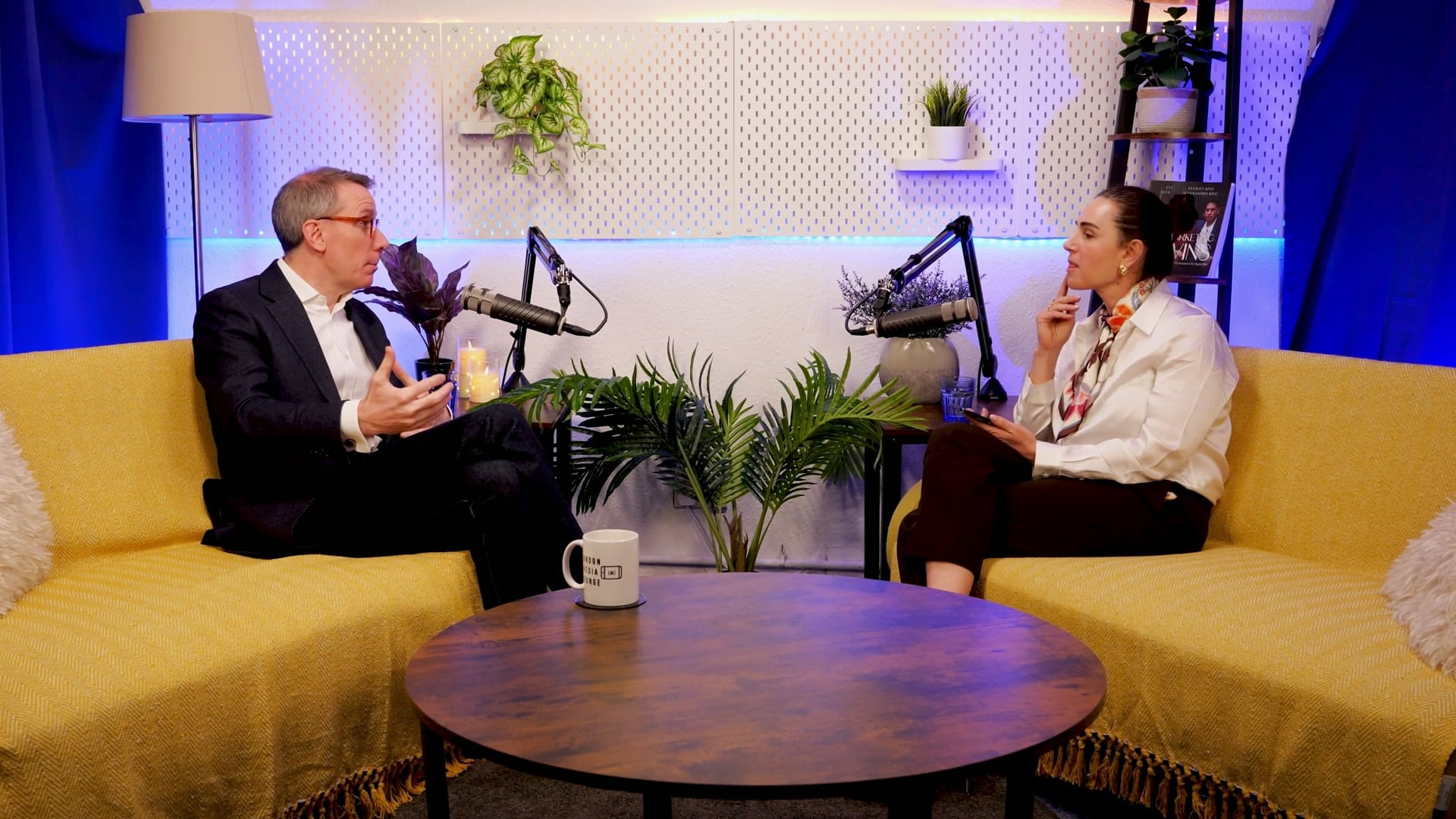 Geoff White and host Aleksandra King in conversation on the BEYOND set, seated either side of a low table with podcast mics between them