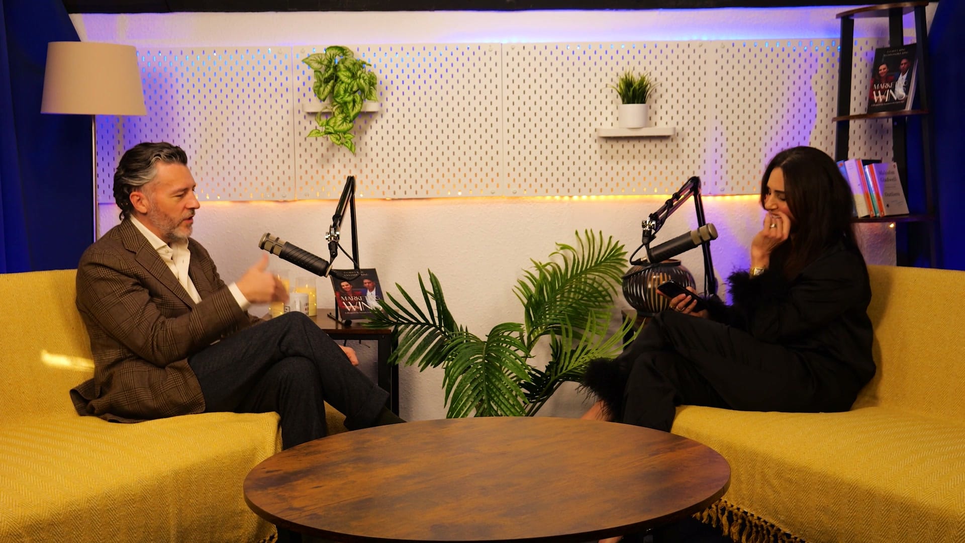 Anthony Flynn and host Aleksandra King in conversation on the BEYOND set, seated either side of a low round table with podcast mics between them