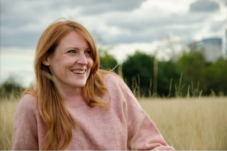 Emily Hughes, former teacher and parenting expert, sitting in a field