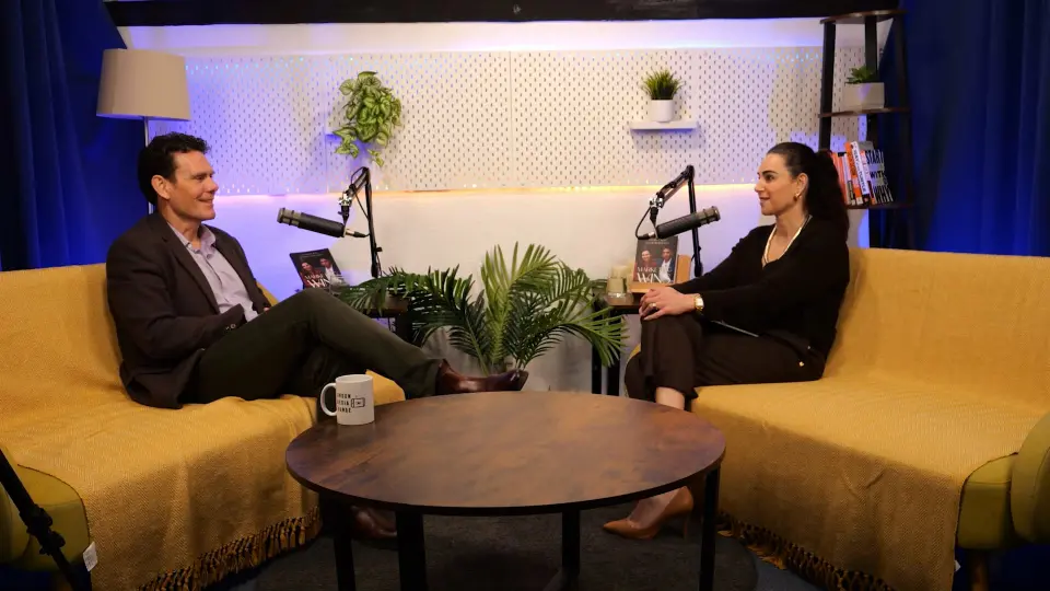 Steve Featherstone and Aleksandra King facing each other across a round table on the BEYOND set, both on mustard sofas with boom microphones between them