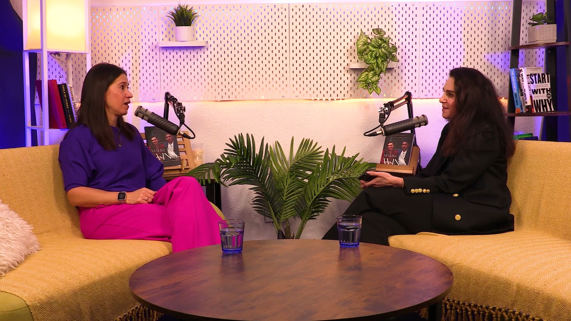 Wide shot of Anna Hemmings and Aleksandra King in conversation across the coffee table on The BEYOND Podcast set