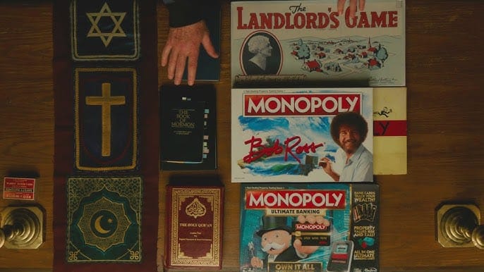 Screenshot from Heretic. An overhead view of a table where Mr. Reed has lined up various versions of the board game Monopoly and the religious texts he says correspond to each one in his explanation of iteration.