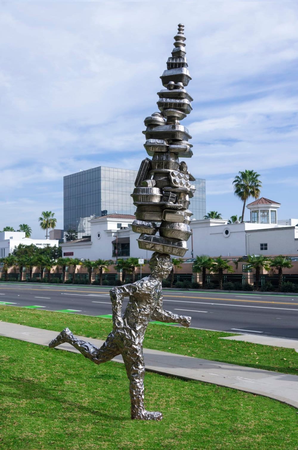 Silver statue of a runner with dozens of to-go food containers stacked on its head