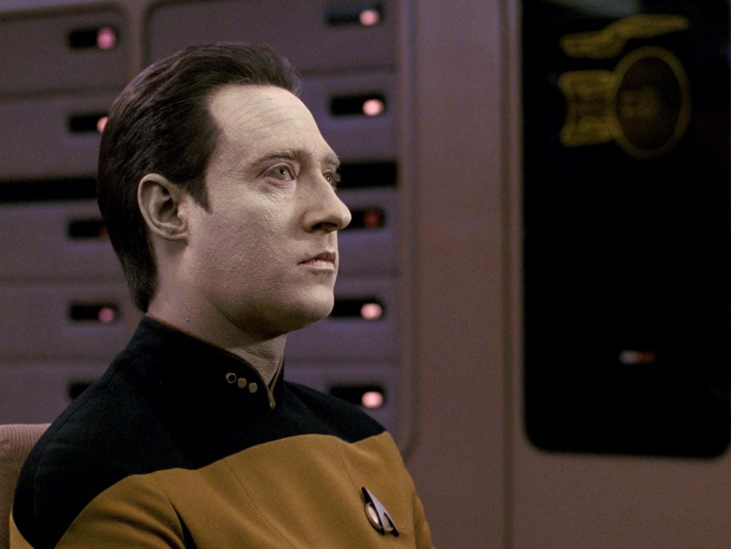 Lieutenant Commander Data stares into the middle distance on the Enterprise-D bridge.