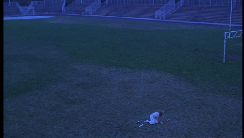 The Virgin Suicides: Lux pushes herself off the ground, alone on the empty football field.