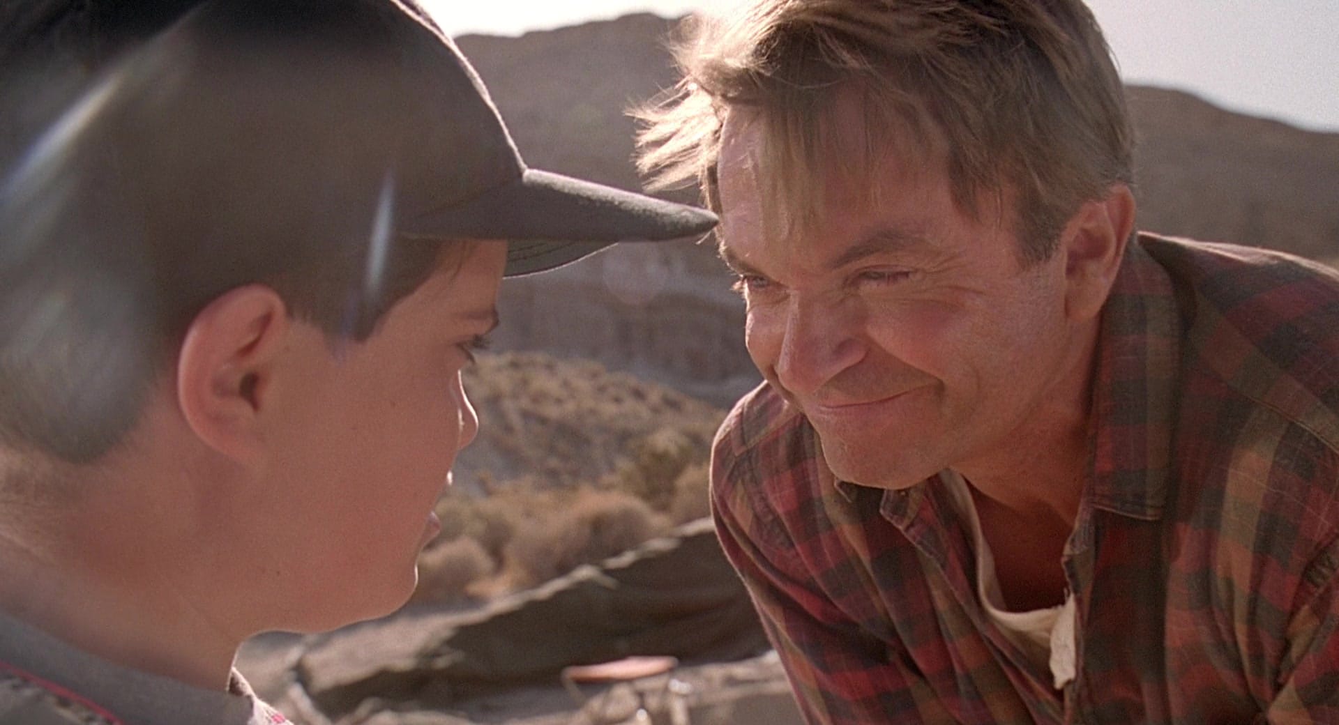 Jurassic Park: Dr. Alan Grant kneels down to eye level with a scared kid, smirking like a real asshole.